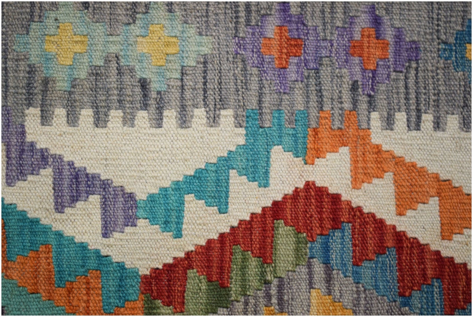 A close-up of a handmade Afghan Maimana kilim featuring geometric patterns in vibrant colors.