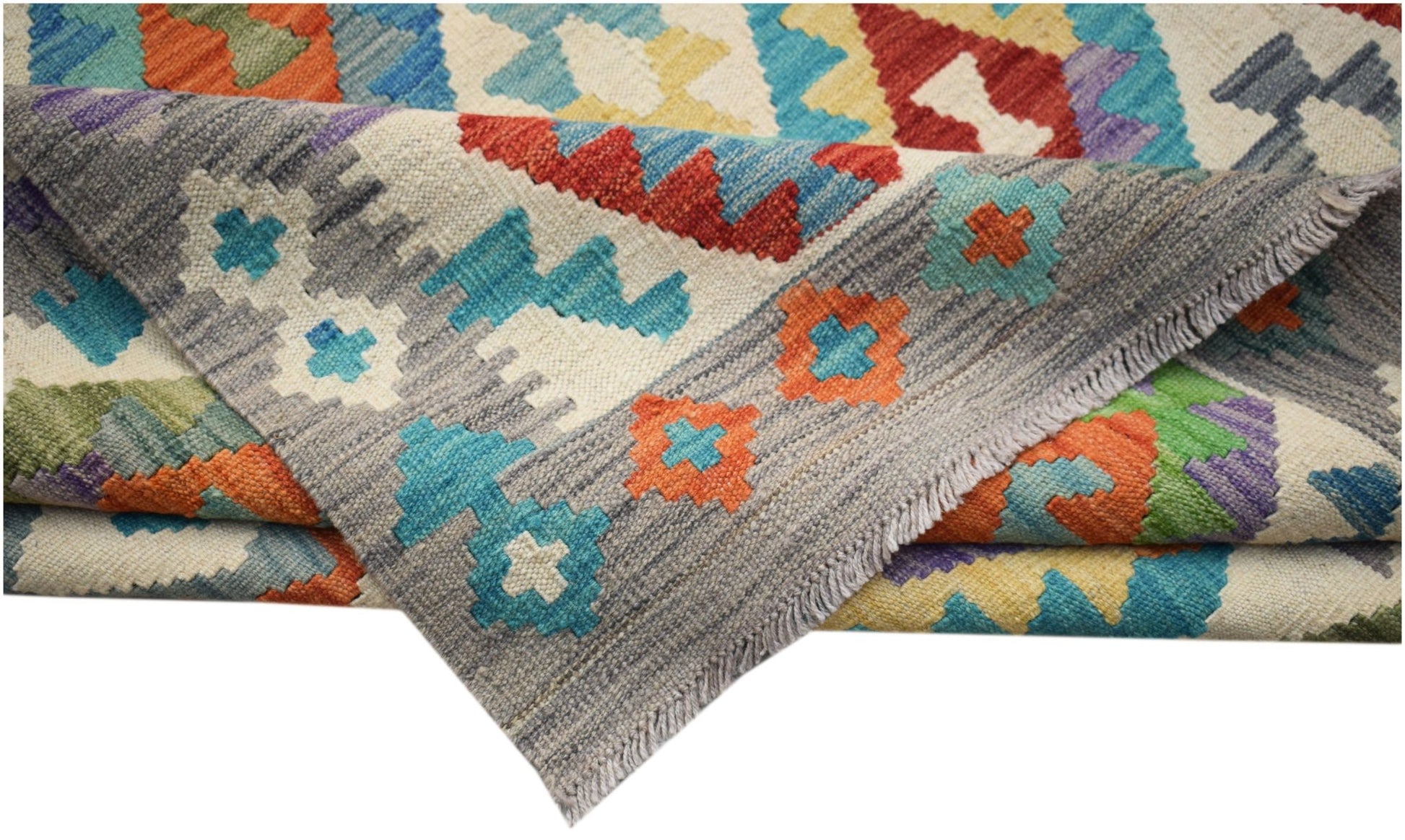 A handwoven Afghan Maimana kilim rug featuring a colorful geometric pattern on a grey background.