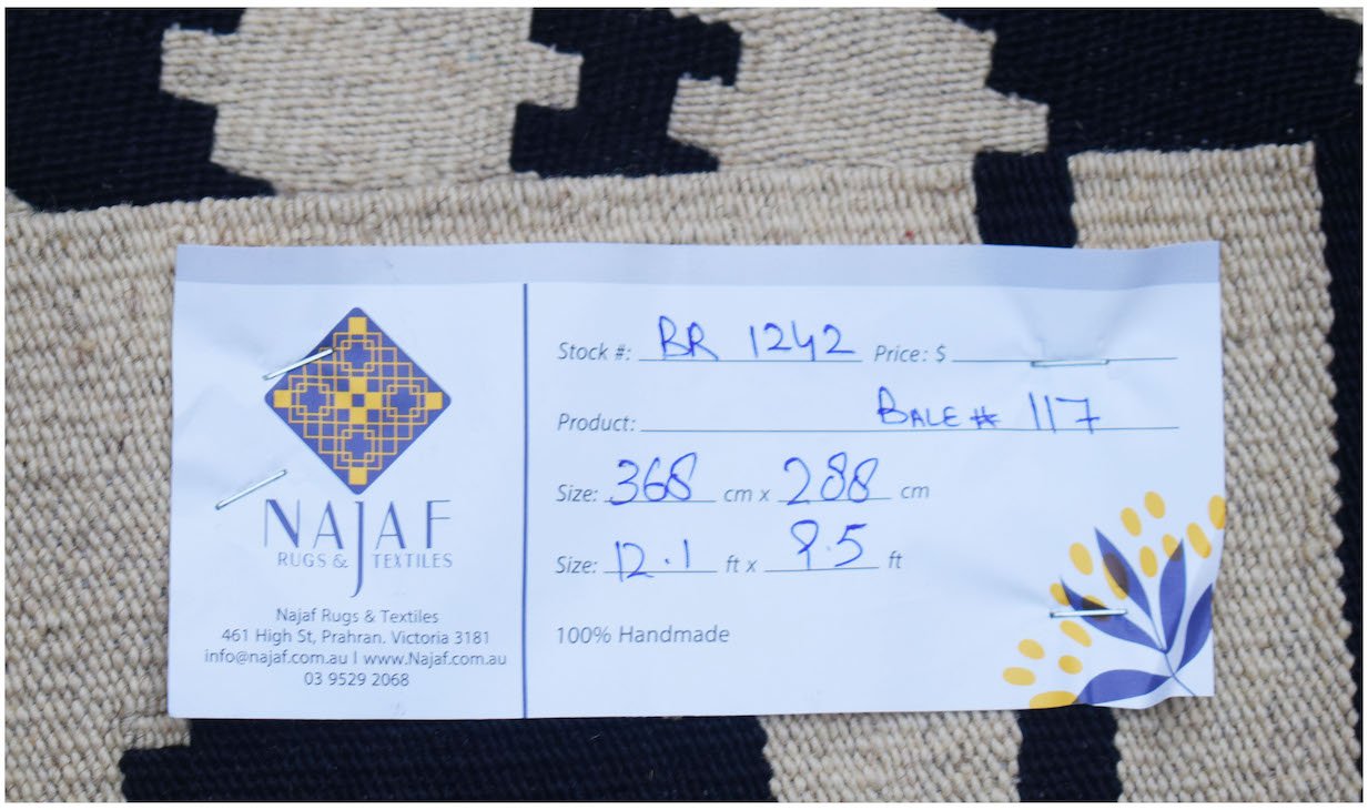 A handmade Afghan Maimana Kilim rug featuring a geometric black and cream pattern.