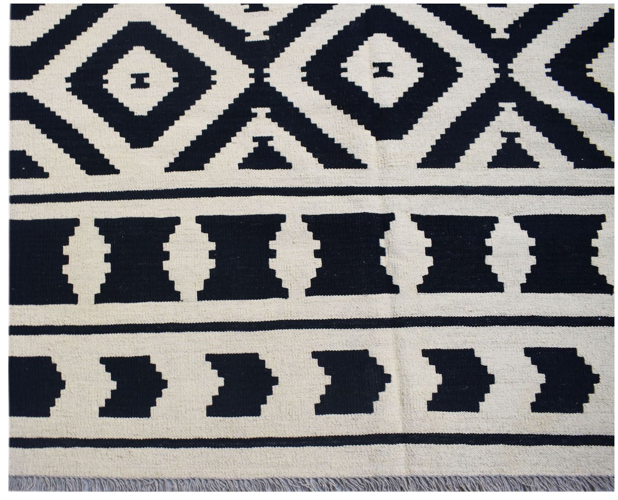 Handwoven Afghan Maimana kilim rug featuring a black and cream geometric pattern.