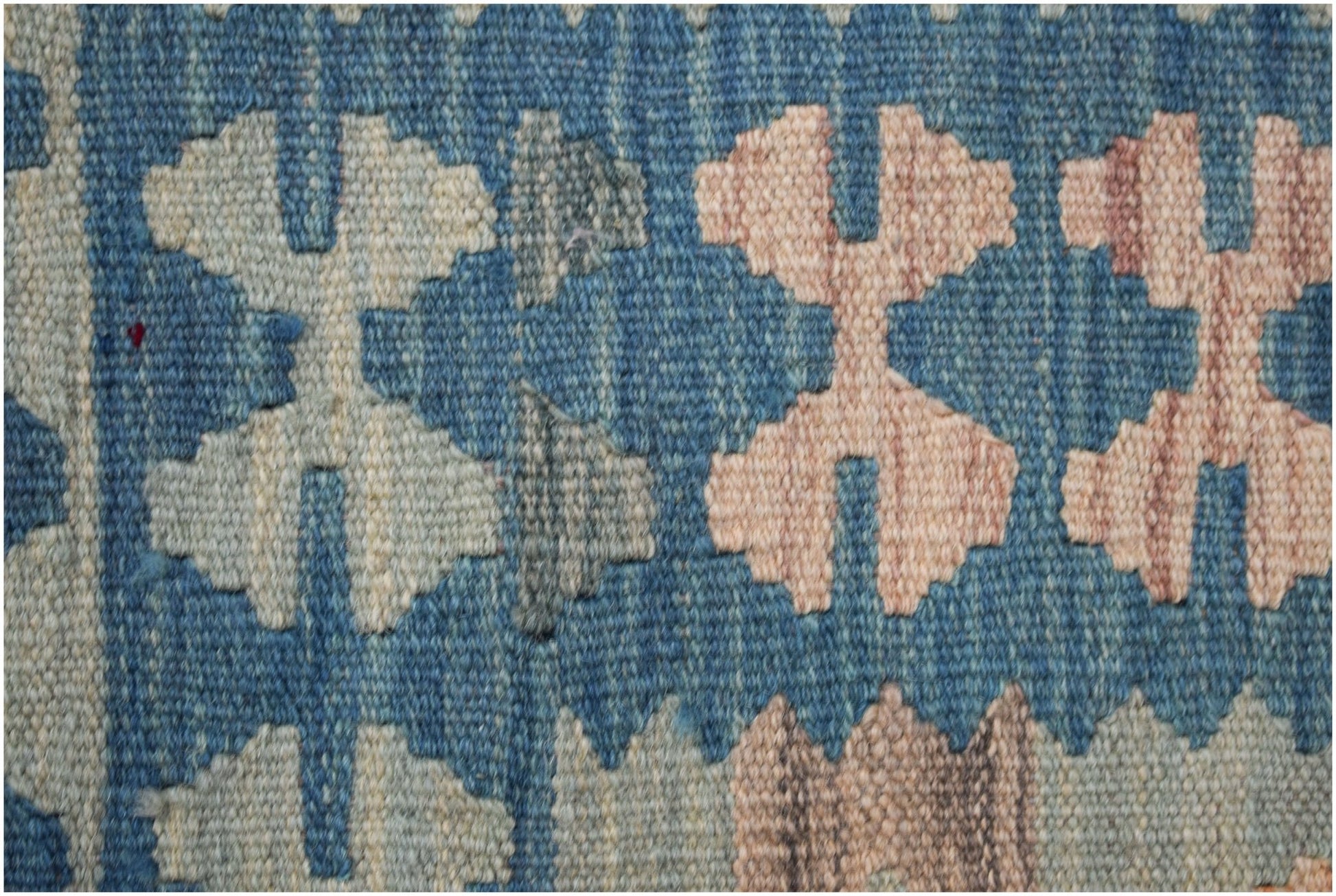 A close-up of a handmade Afghan Maimana kilim runner featuring geometric patterns in blue and tan.