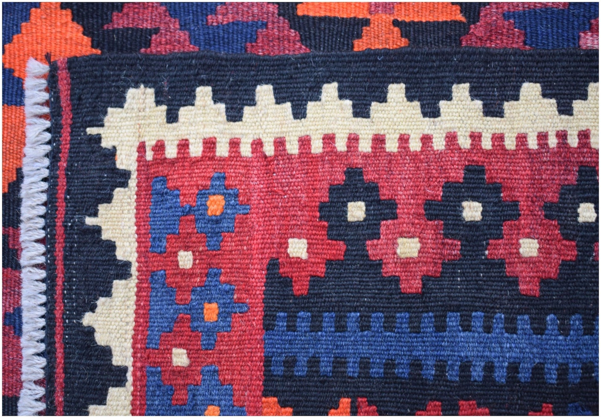 A handmade Afghan Maimana kilim runner featuring geometric patterns in red, blue, and cream wool.