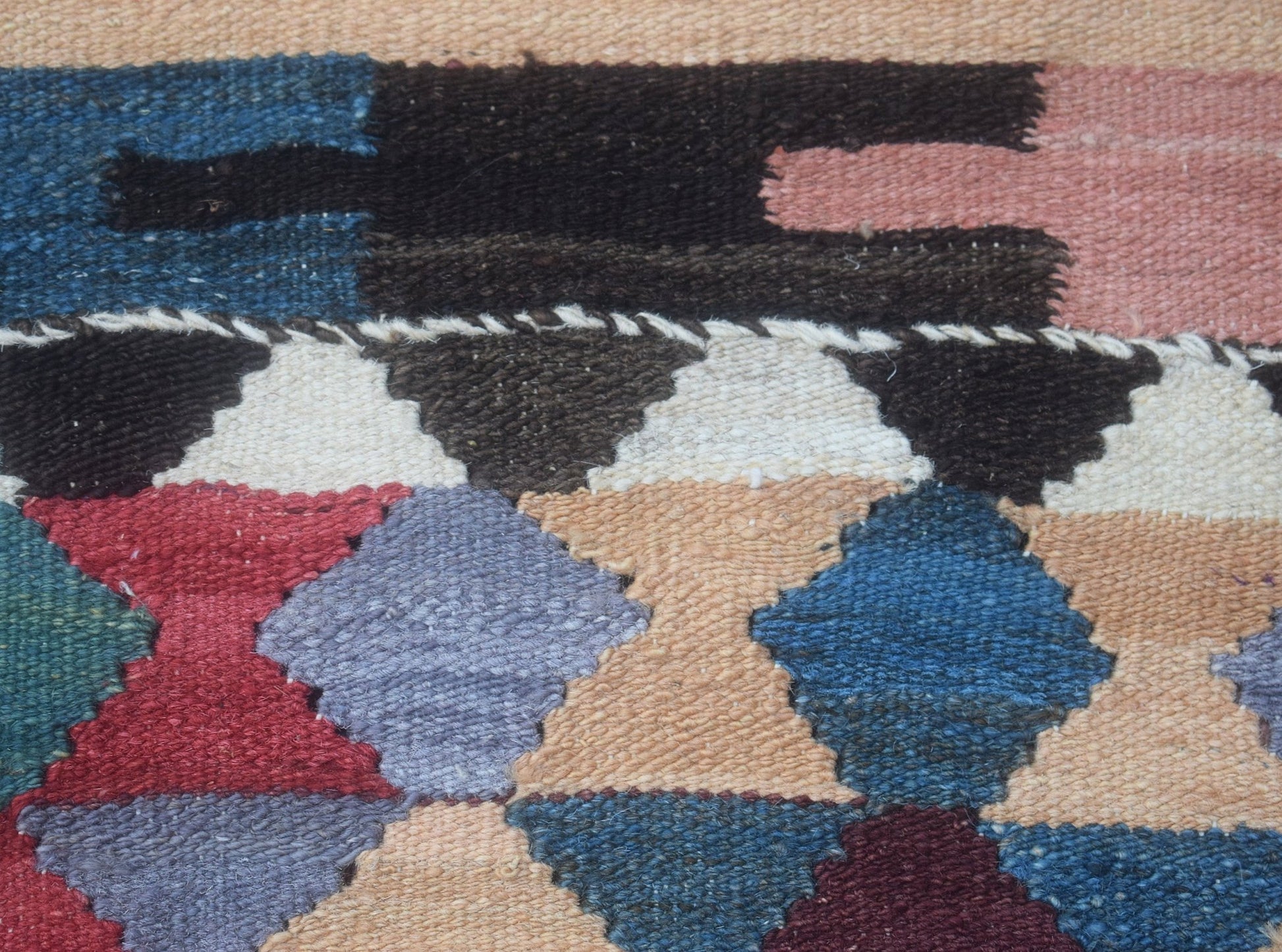 A close-up of a handmade Afghan Maimana kilim runner featuring a geometric pattern in wool.