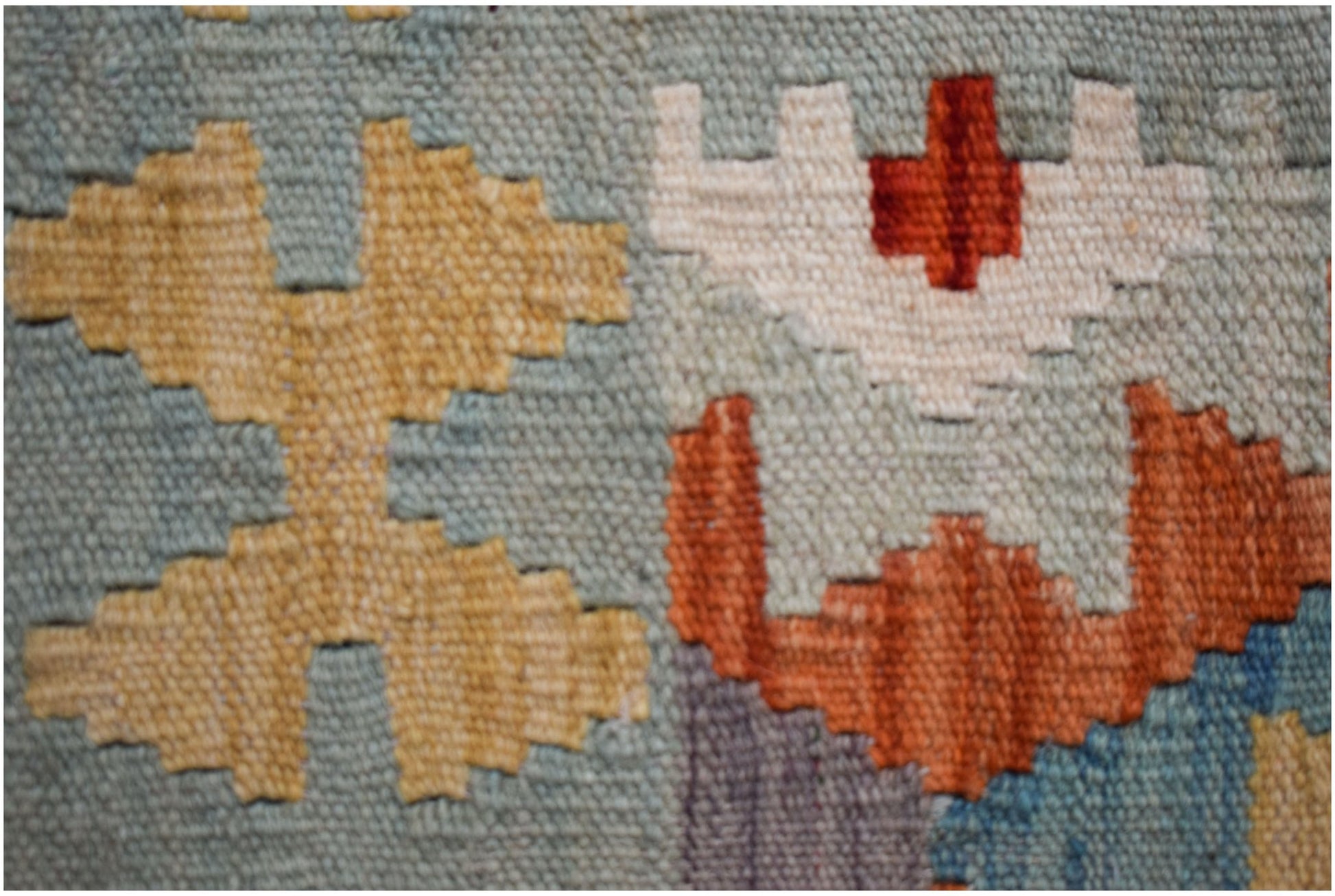 A close-up of a handmade Afghan Maimana kilim runner featuring geometric patterns in wool.
