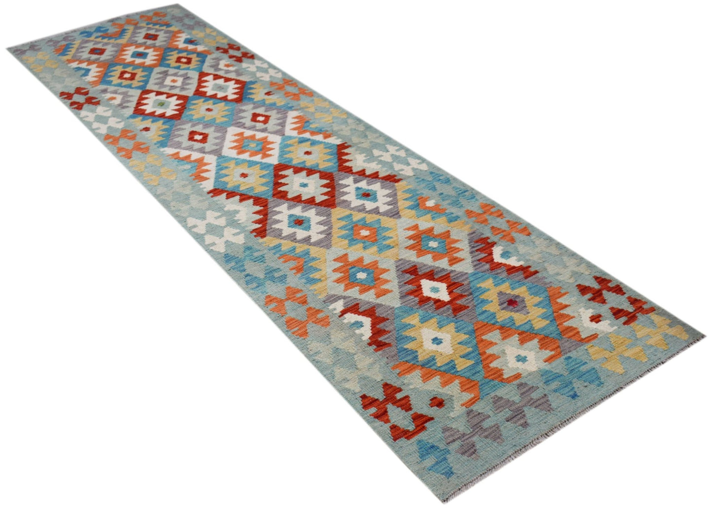 A handmade Afghan Maimana wool runner rug featuring a colorful geometric pattern on a blue base.
