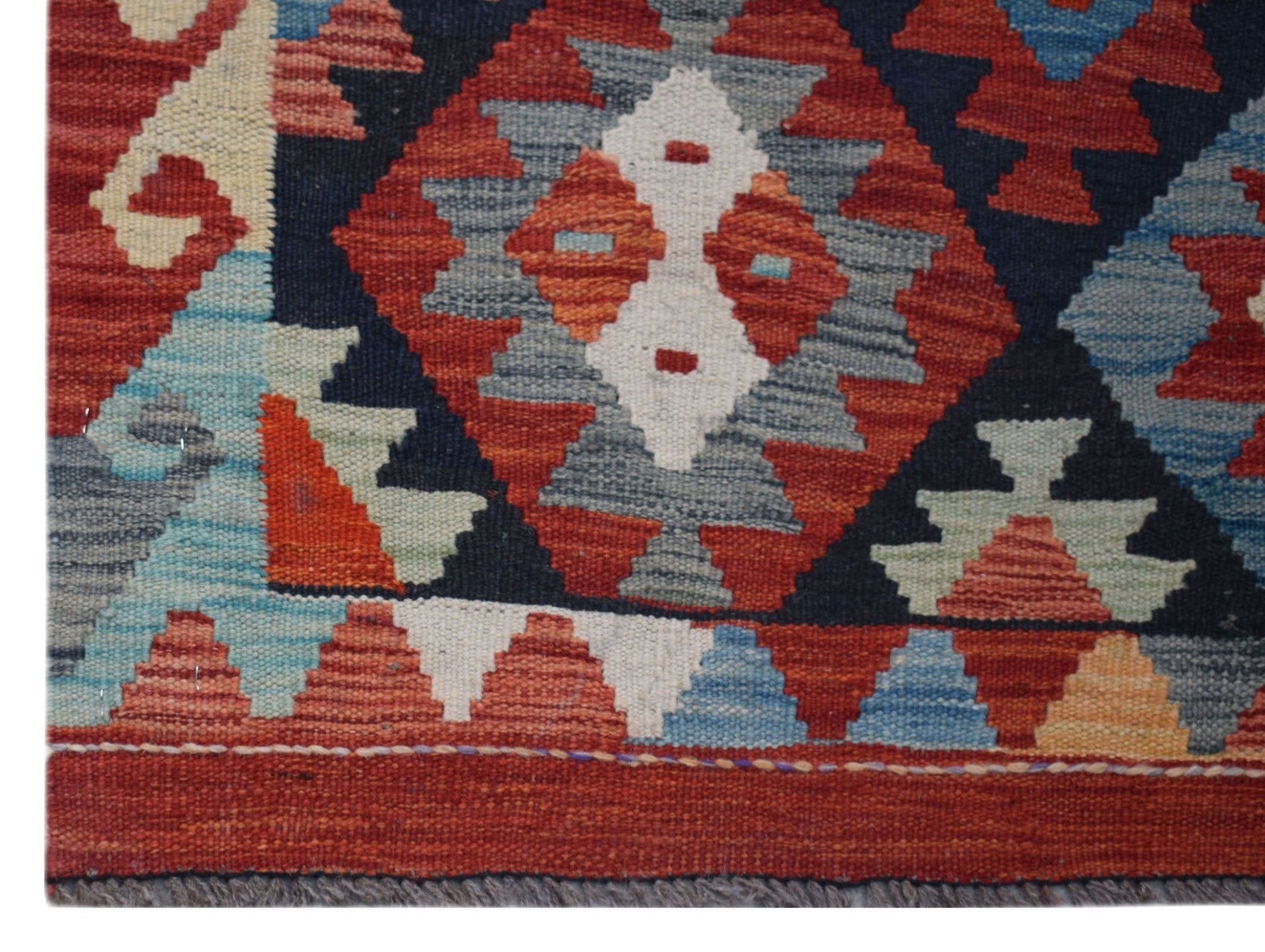 Handwoven Afghan Maimana kilim runner featuring a geometric pattern in red, blue, and cream wool.