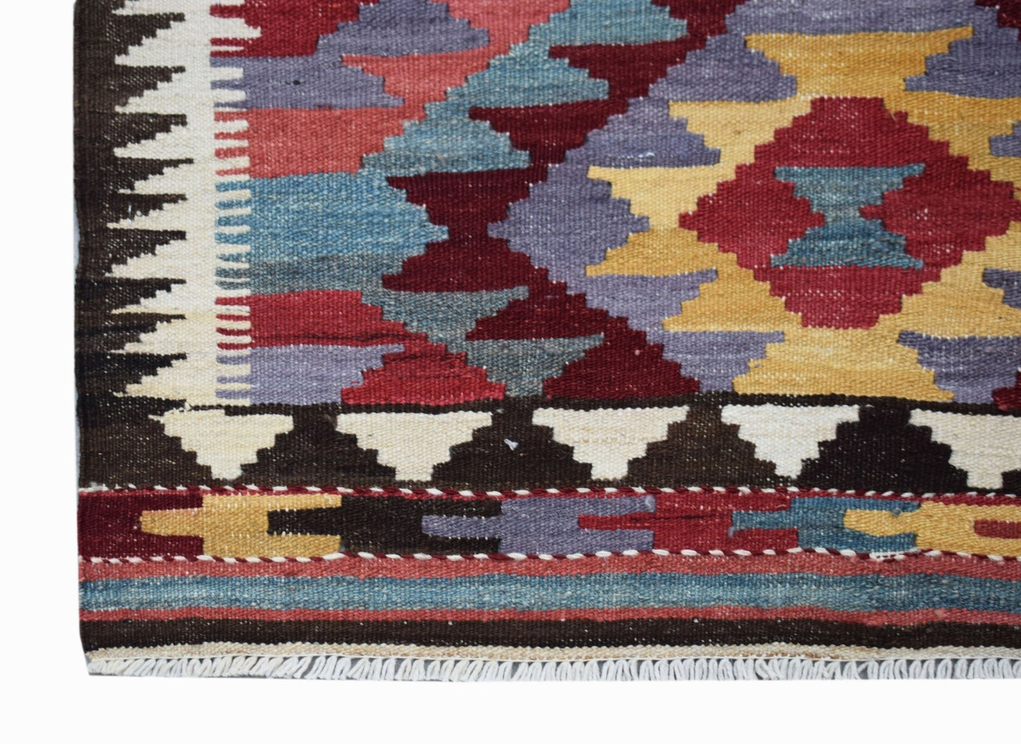 A handmade Afghan Maimana wool runner featuring a geometric pattern in red, blue, and yellow.