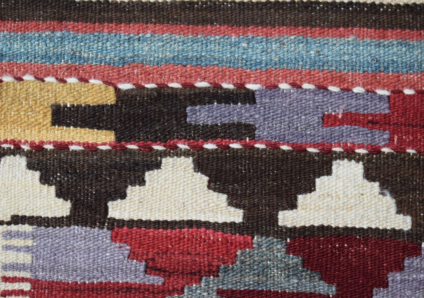 A close-up of a handmade Afghan Maimana wool kilim runner featuring geometric patterns and colors.