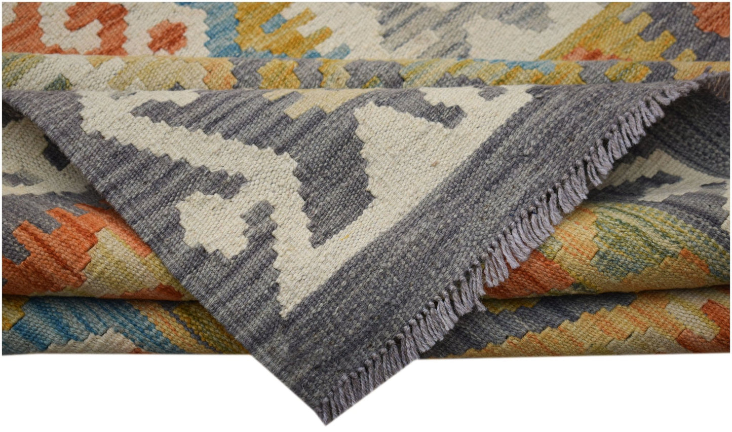 A folded Afghan Maimana kilim runner featuring a geometric pattern in orange, blue, and grey wool.