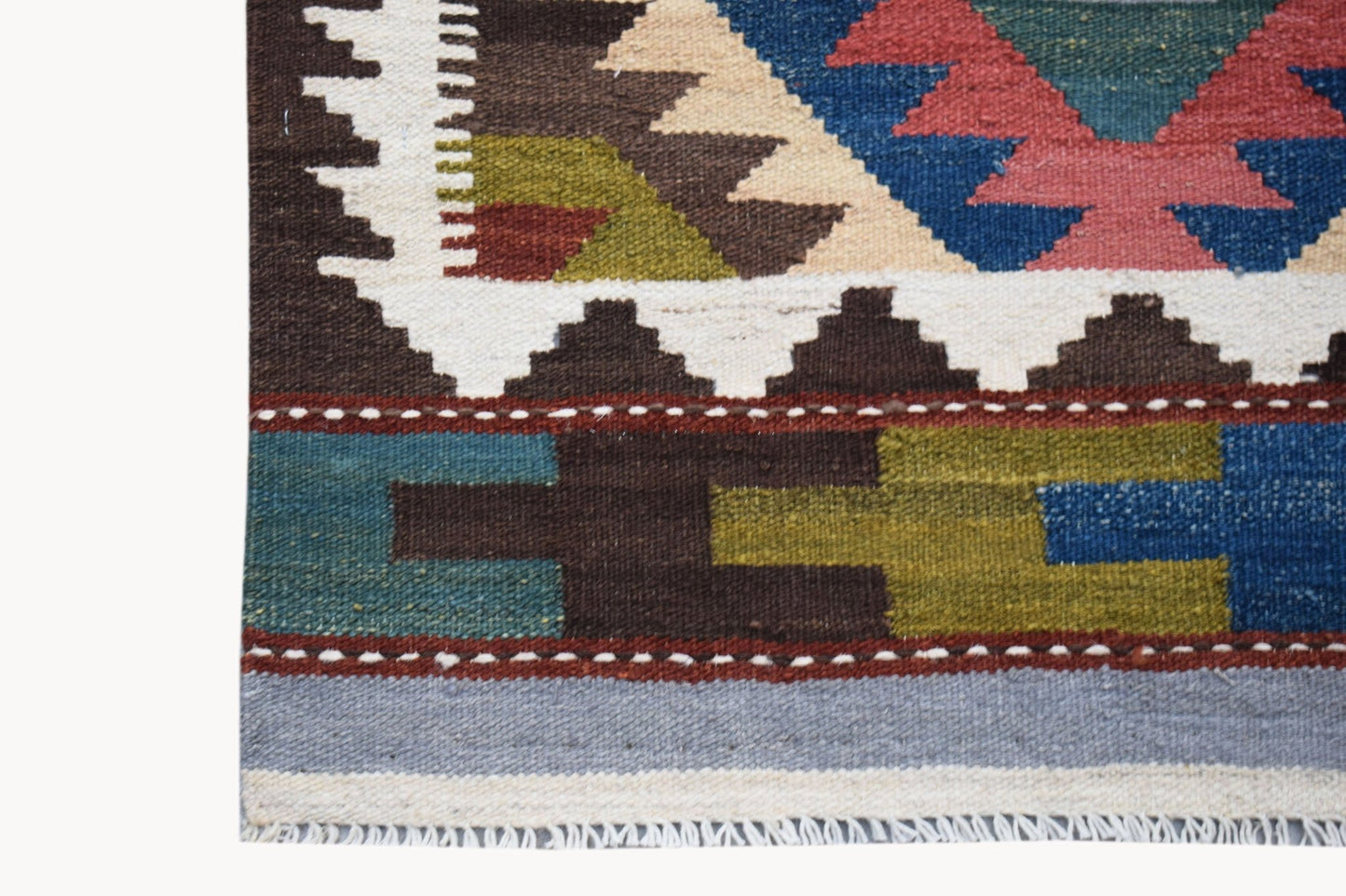 A handmade Afghan Maimana kilim runner featuring geometric patterns in blue, red, and olive wool.