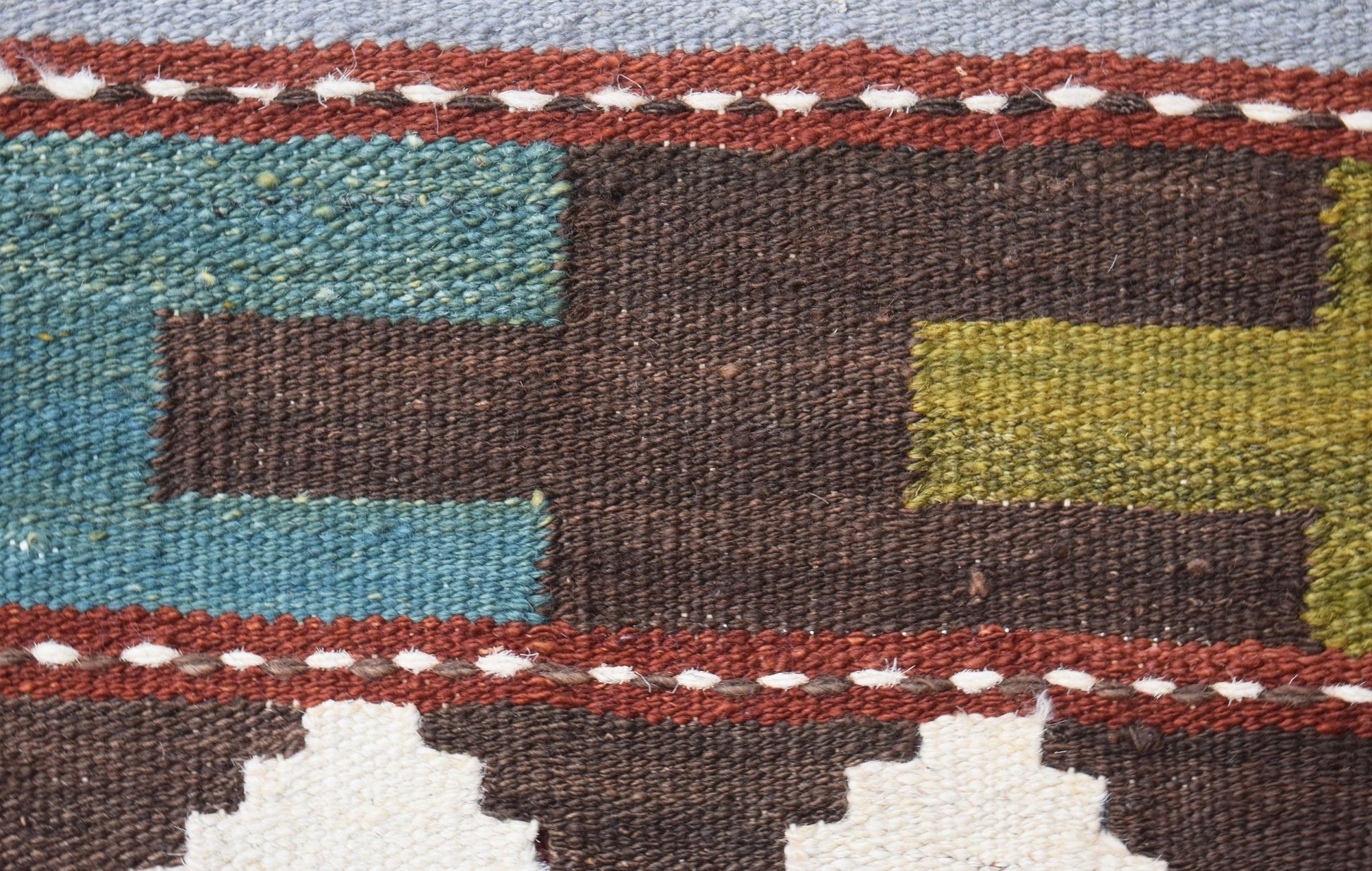 A close-up of a handmade Afghan Maimana kilim runner featuring geometric patterns in wool.