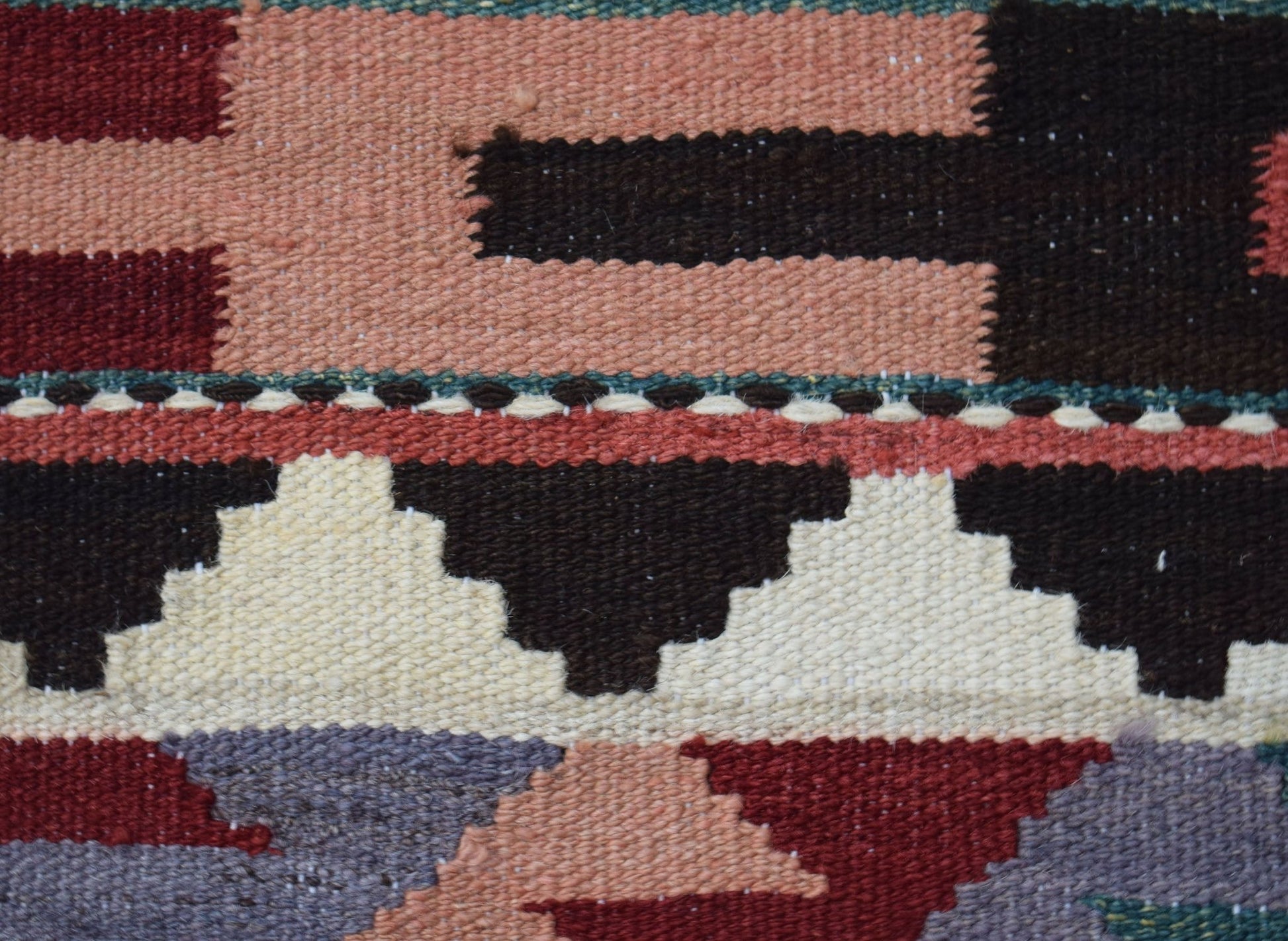 A close-up of a handwoven Afghan Maimana kilim featuring geometric patterns in wool.