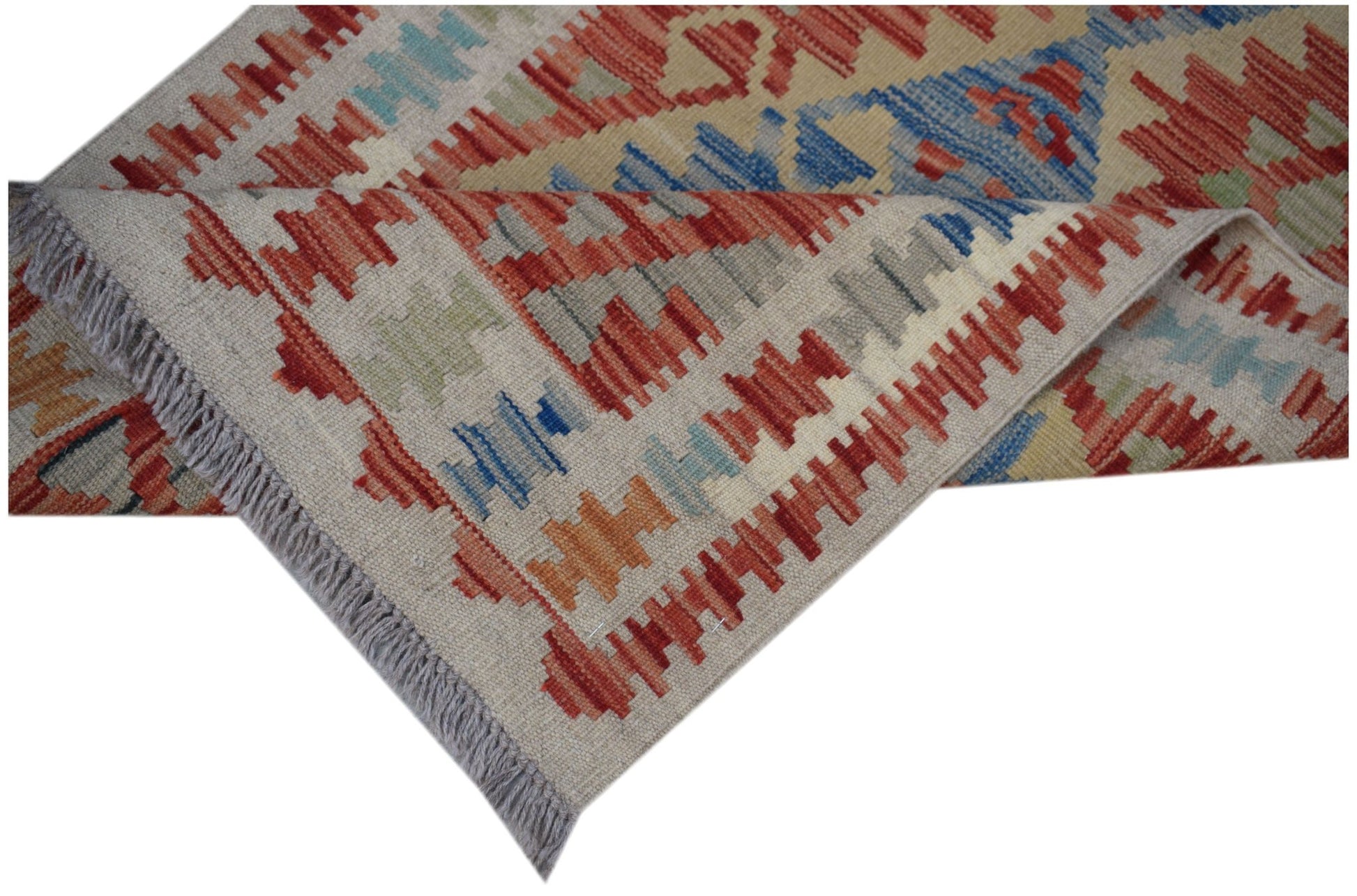 A handmade Afghan Maimana wool runner rug featuring a geometric pattern in red, blue, and tan.