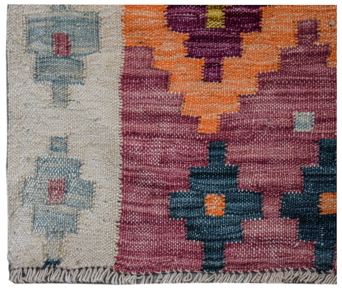 Handwoven Afghan Maimana wool kilim runner featuring geometric patterns in orange, pink, and blue.