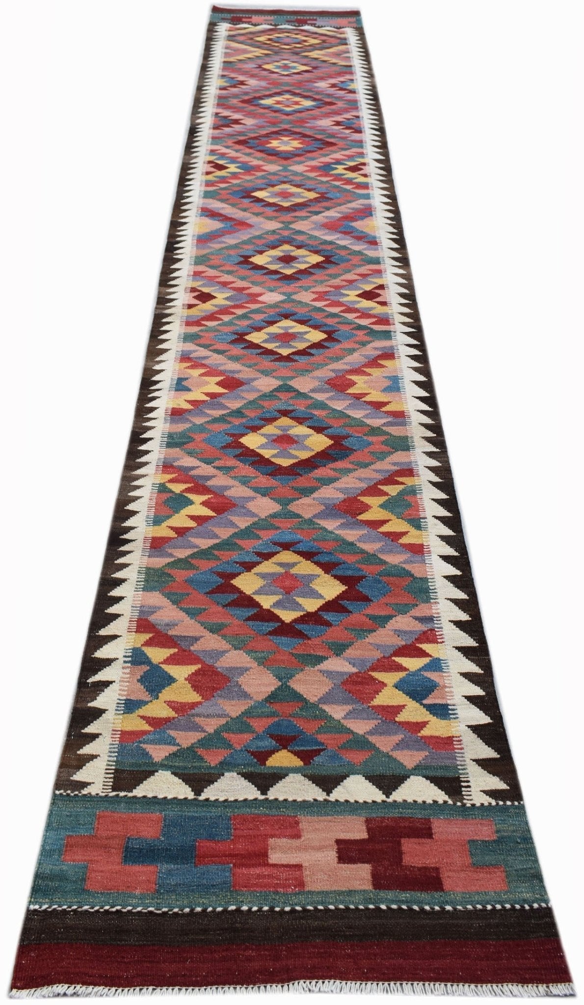 A long, handmade Afghan Maimana wool runner rug featuring a colorful geometric diamond pattern.