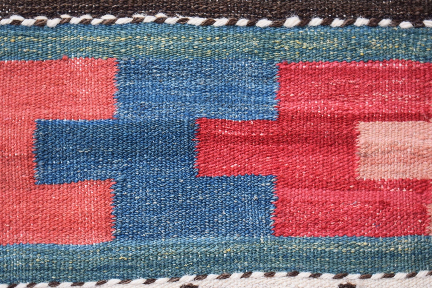A close-up of a handmade Afghan Maimana kilim runner featuring geometric red and blue patterns.