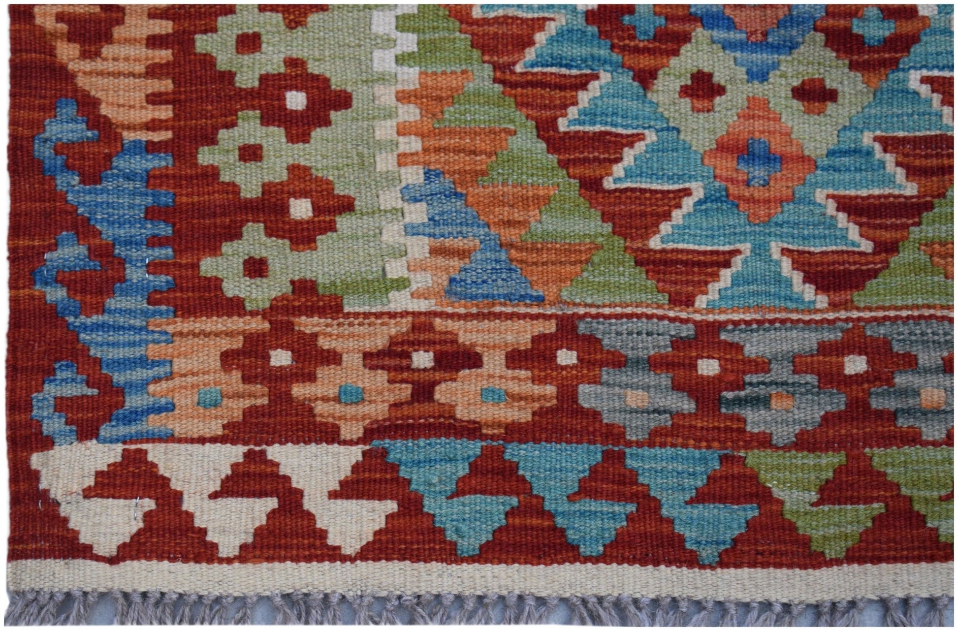 Handwoven Afghan Maimana kilim rug featuring a geometric pattern in vibrant red, blue, and green.