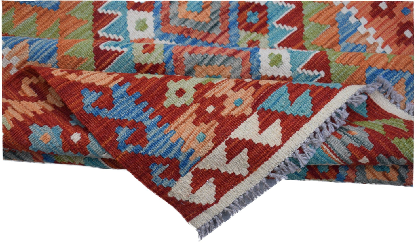 A handwoven Afghan Maimana kilim rug featuring a vibrant geometric pattern in wool.