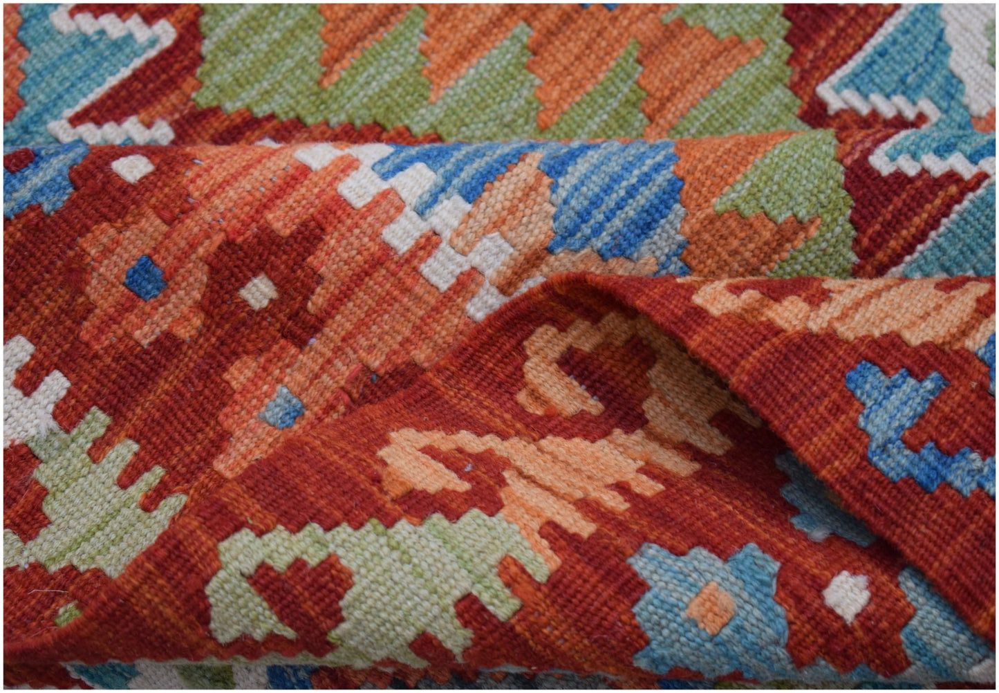 A handwoven Afghan Maimana kilim rug featuring a vibrant geometric pattern in wool.