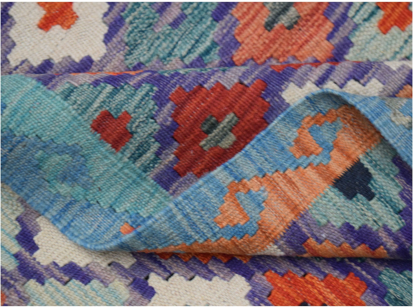 A handwoven Afghan Maimana kilim rug featuring a vibrant geometric pattern in wool.