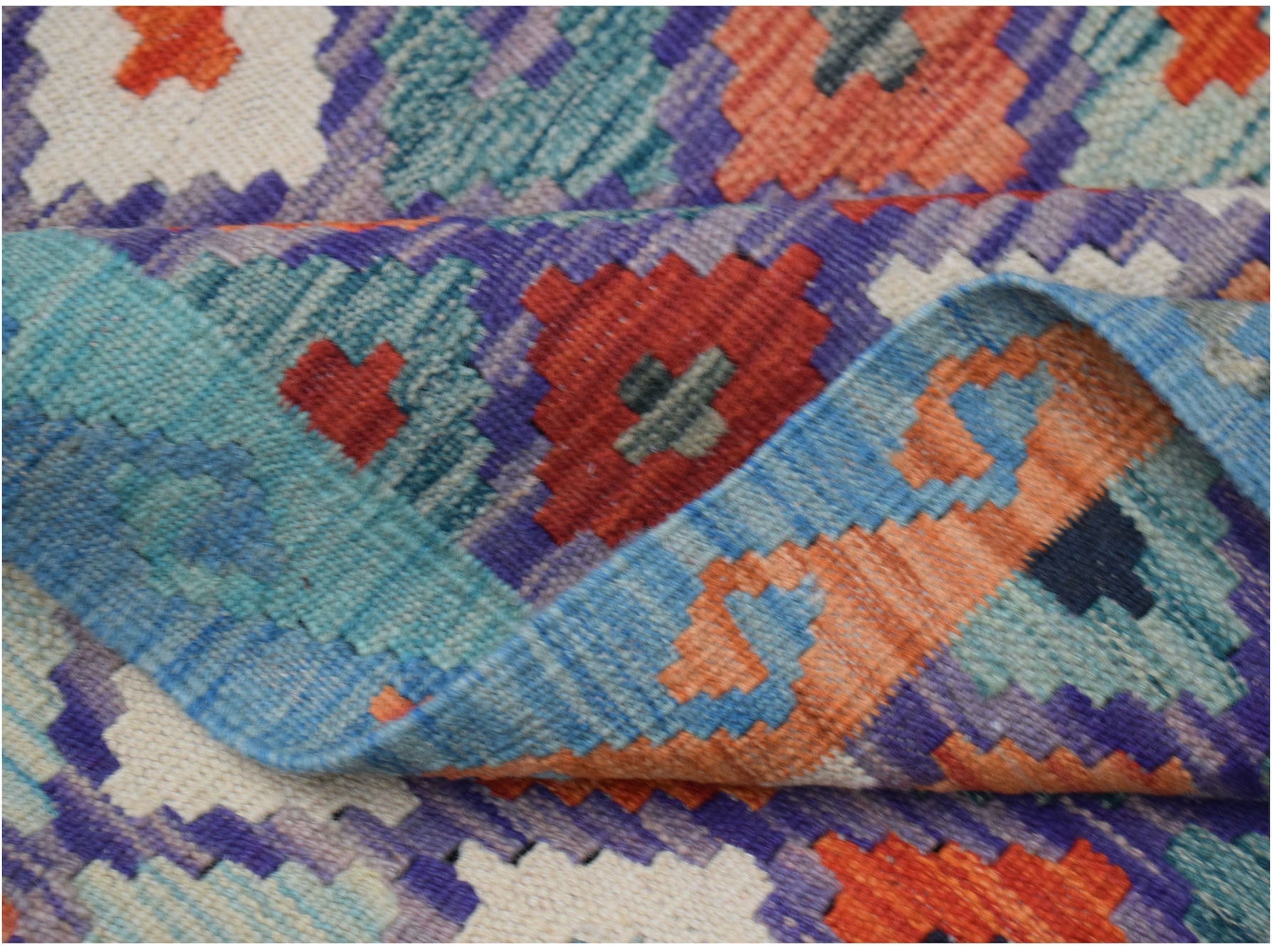 A handwoven Afghan Maimana kilim rug featuring a vibrant geometric pattern in wool.