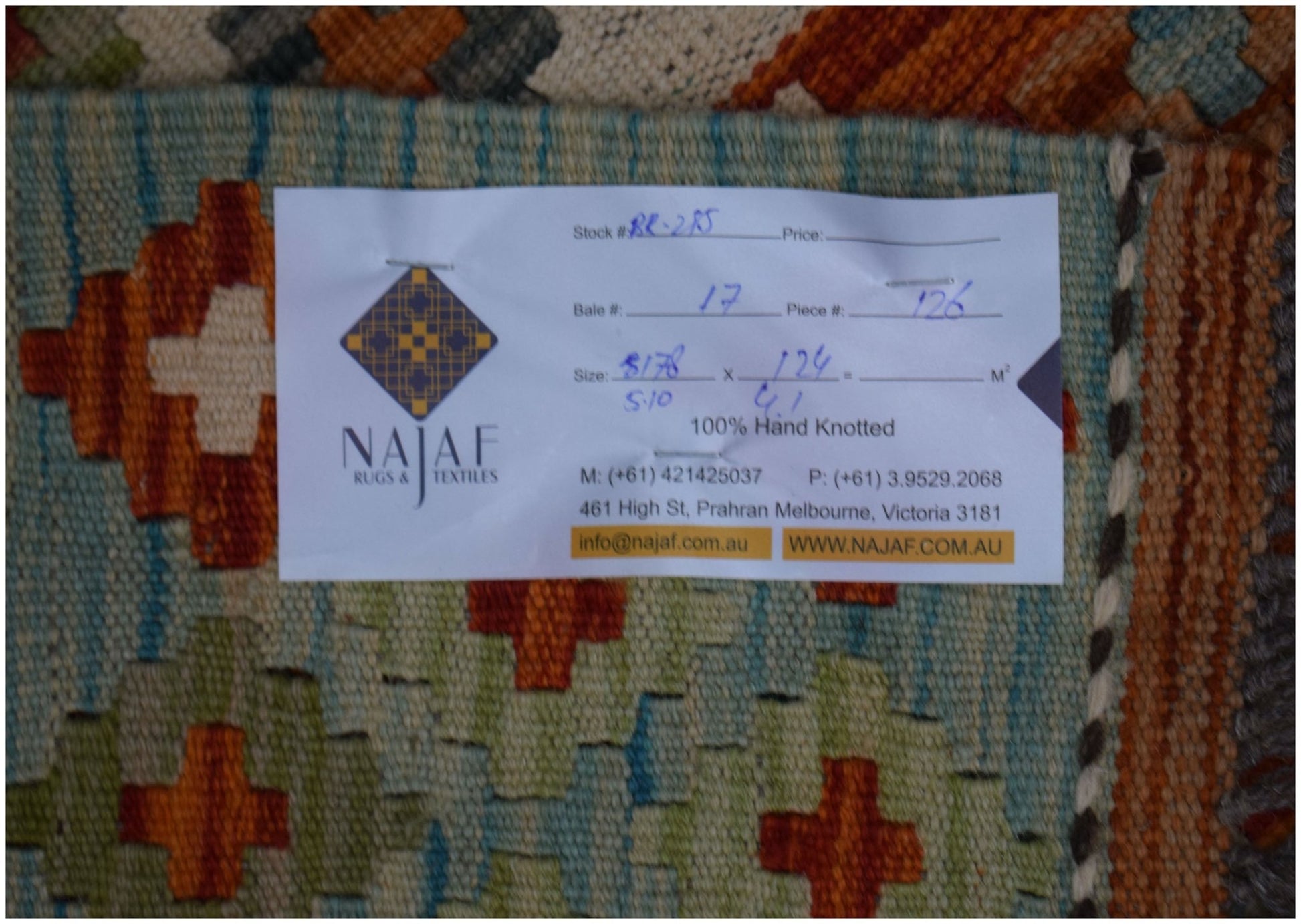 An Afghan Maimana Kilim rug featuring a geometric pattern in vibrant orange, blue, and cream tones.