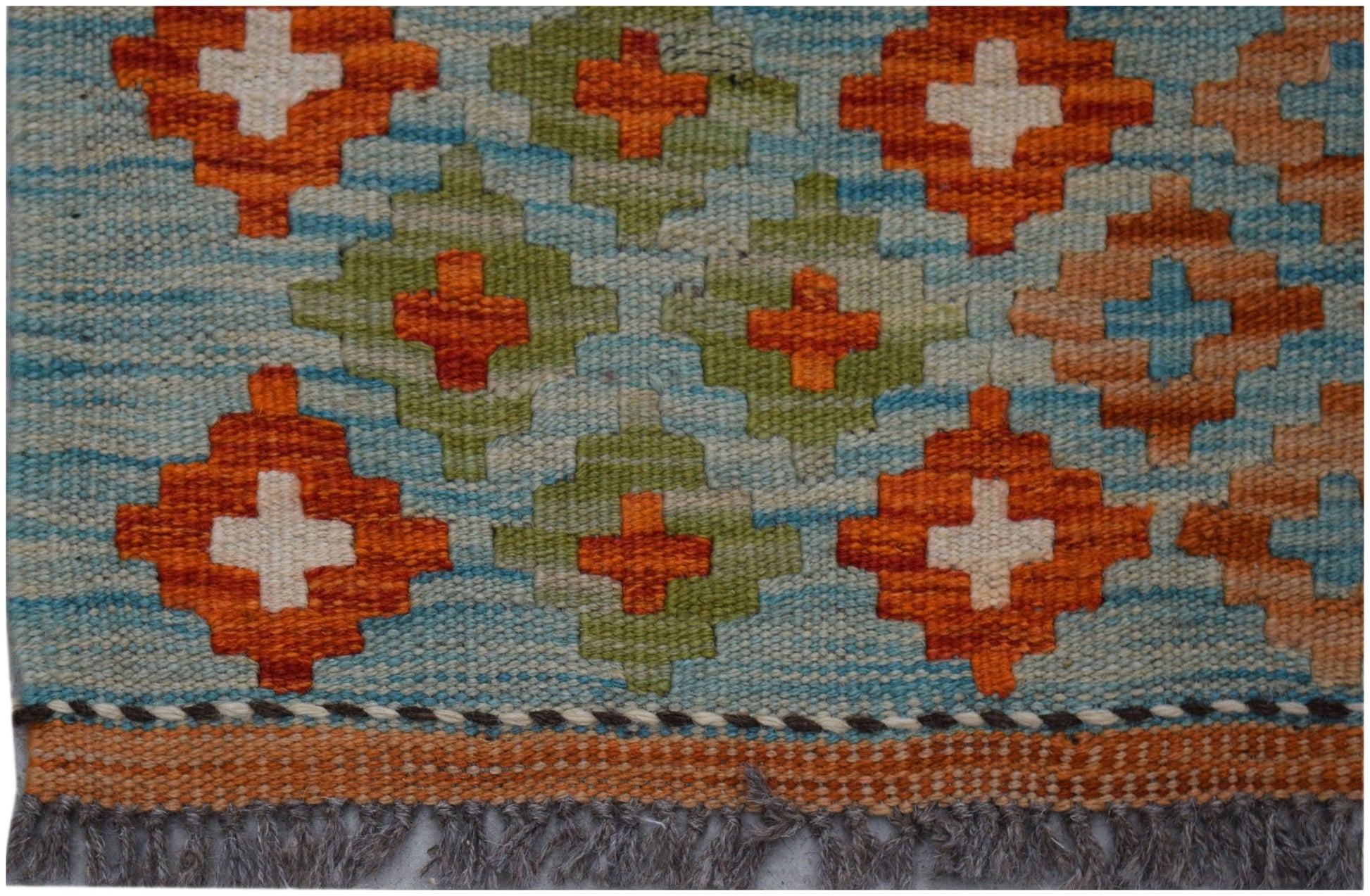 Handwoven Afghan Maimana kilim rug featuring a geometric pattern in orange, green, and blue.