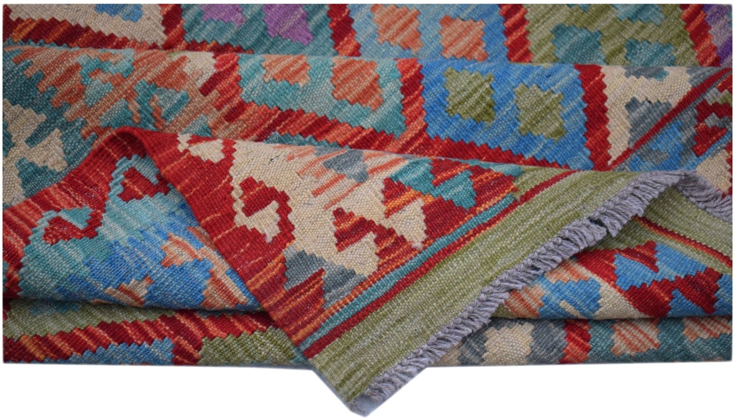 A handwoven Afghan Maimana kilim rug featuring a vibrant geometric pattern in wool.