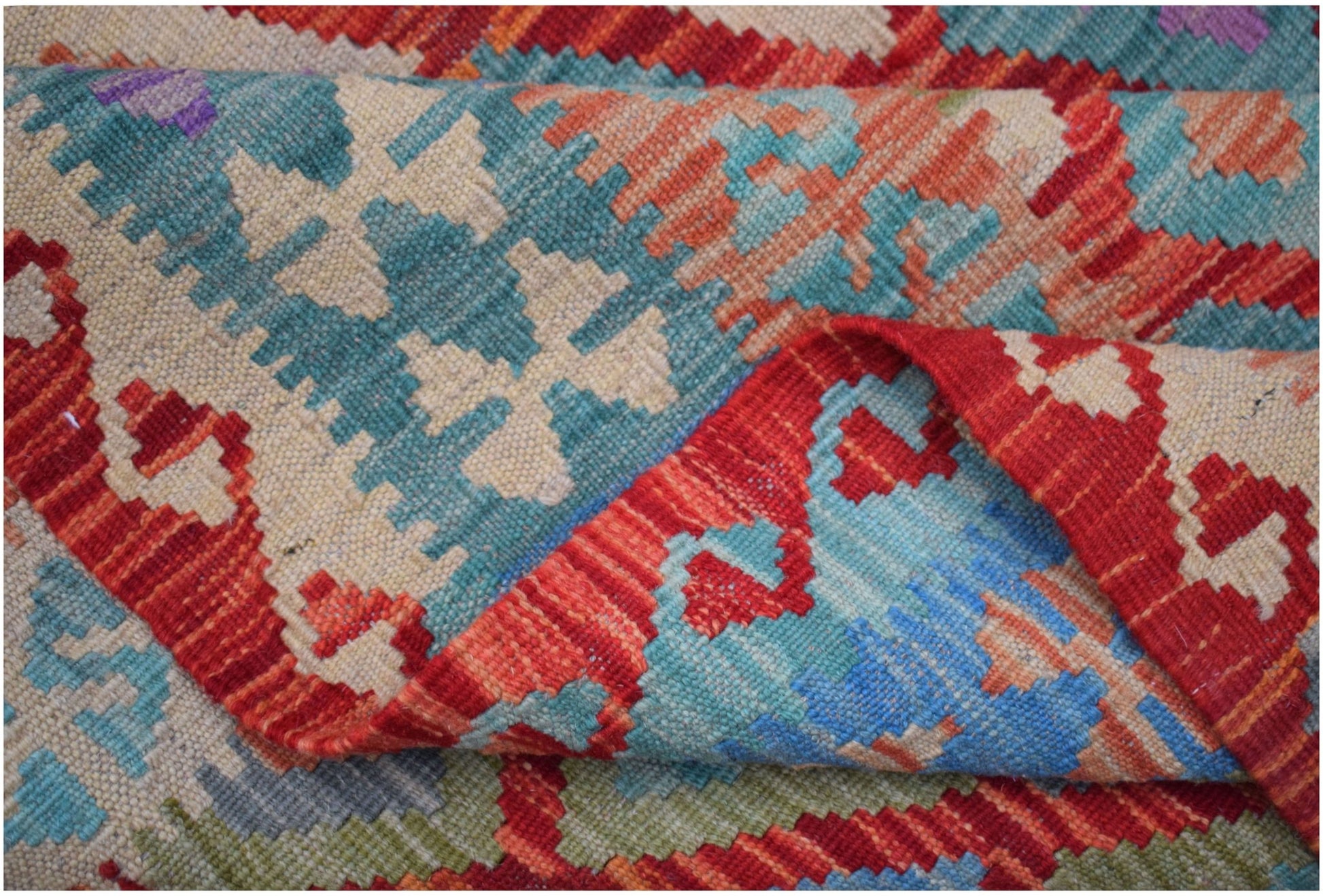A handwoven Afghan Maimana kilim rug featuring a vibrant geometric pattern in wool.