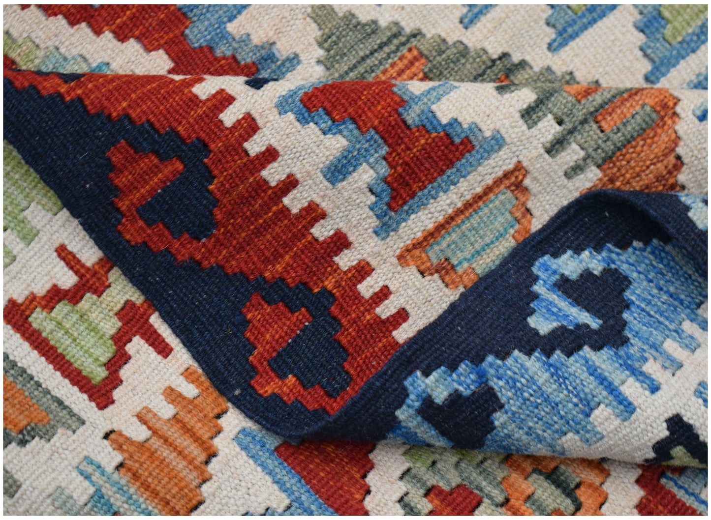 A handmade Afghan Maimana kilim rug featuring a geometric pattern in red, blue, orange, and green.