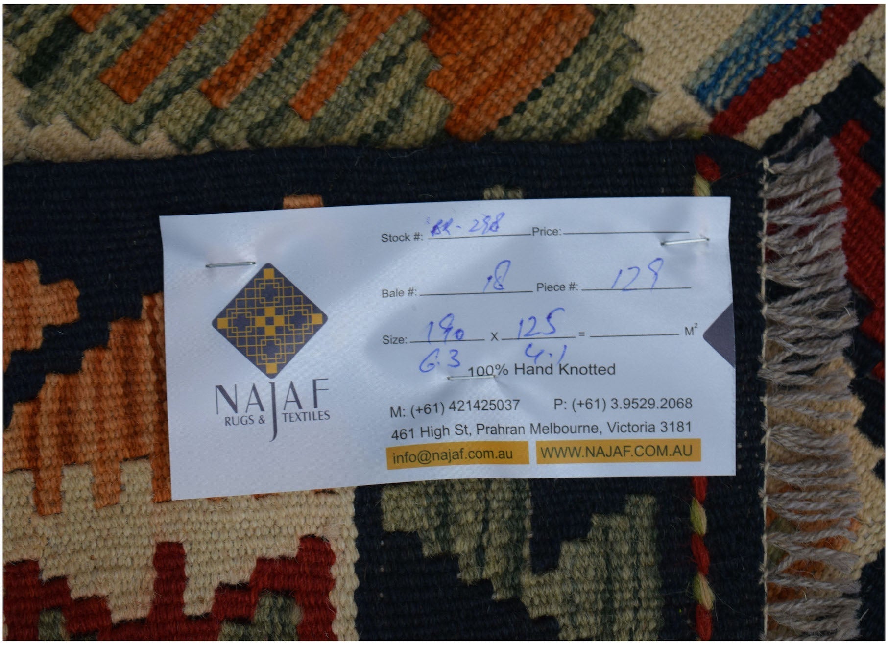 A handwoven Afghan Maimana kilim featuring a geometric pattern in rich, earthy tones.