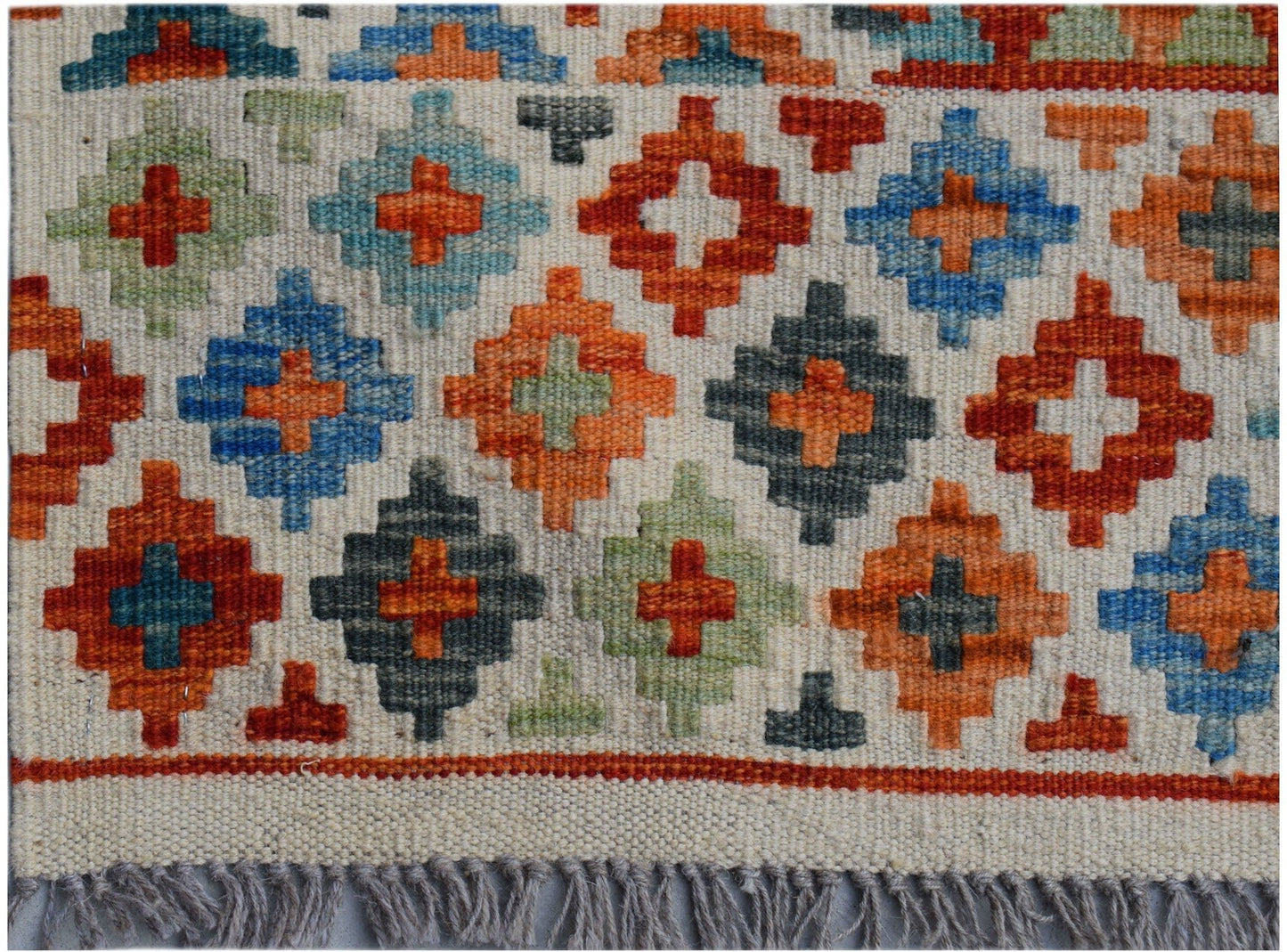 Handwoven Afghan Maimana kilim rug featuring a geometric pattern of colorful diamond motifs.