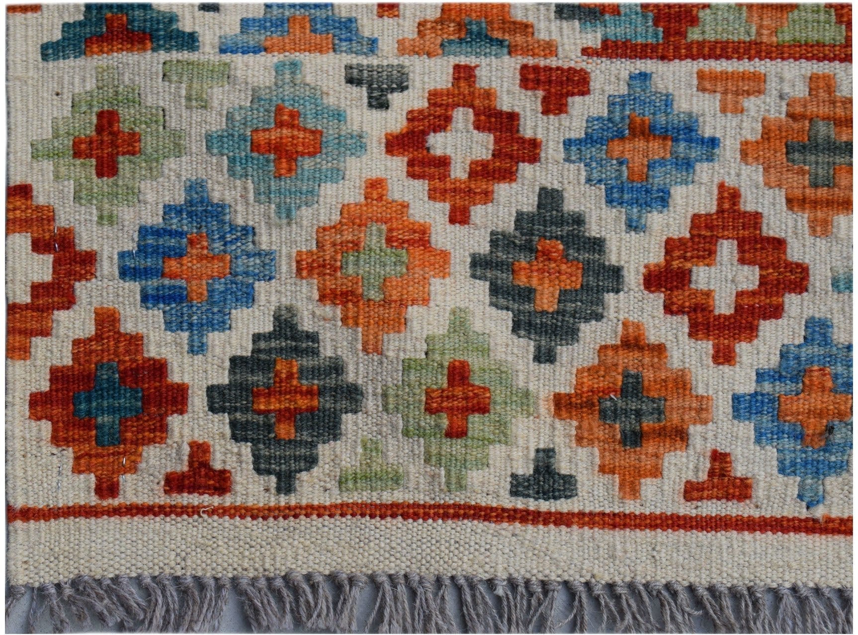 Handwoven Afghan Maimana kilim rug featuring a geometric pattern of colorful diamond motifs.