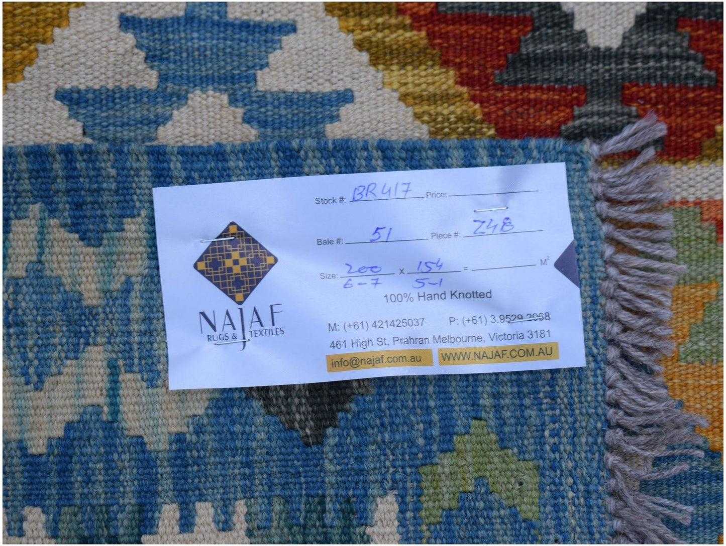 A handwoven Afghan Maimana kilim rug featuring a geometric pattern in blue, orange, and cream.