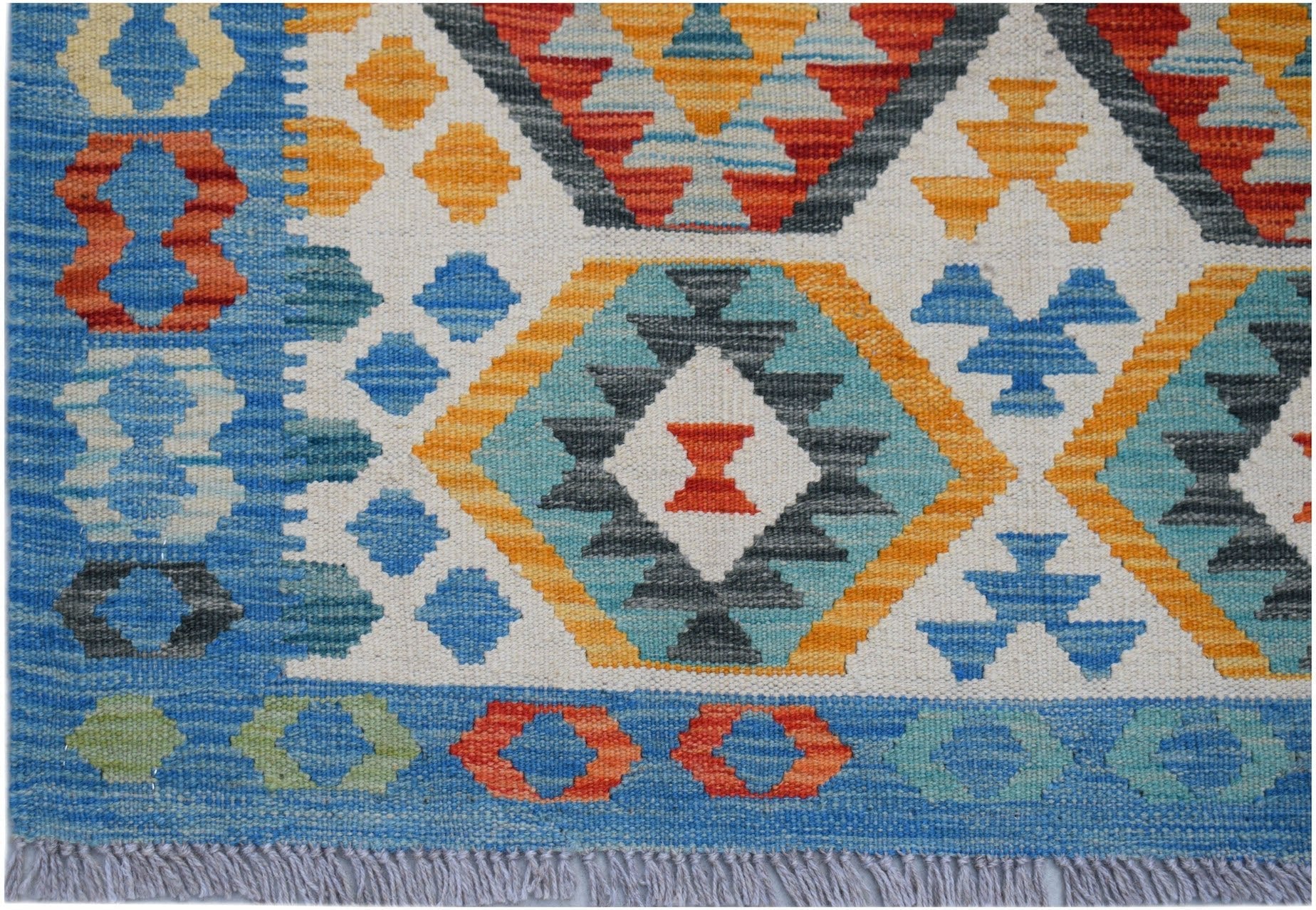 Handwoven Afghan Maimana kilim rug featuring a geometric pattern in blue, orange, and grey tones.