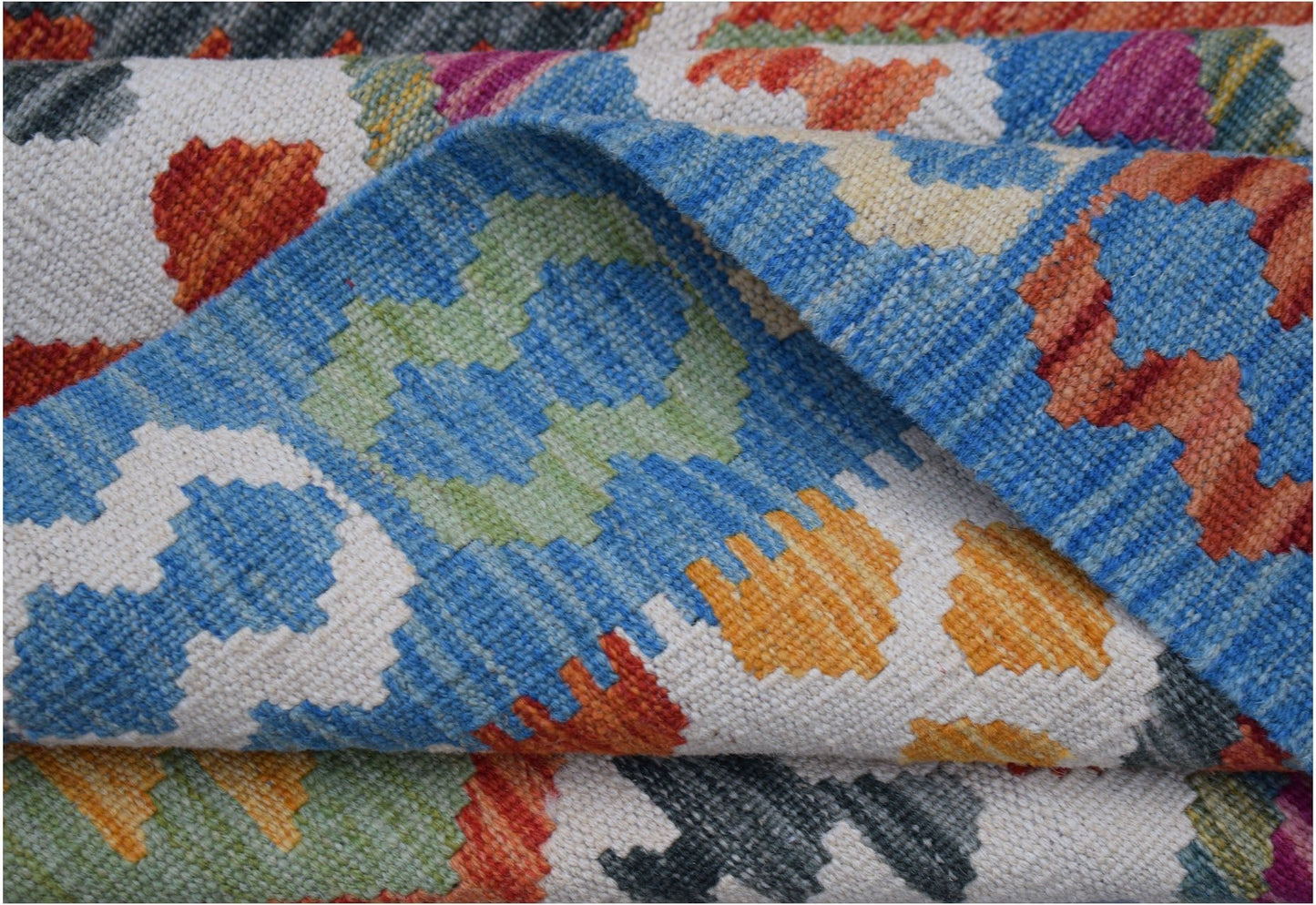 A handwoven Afghan Maimana kilim rug featuring a colorful geometric pattern on a white background.