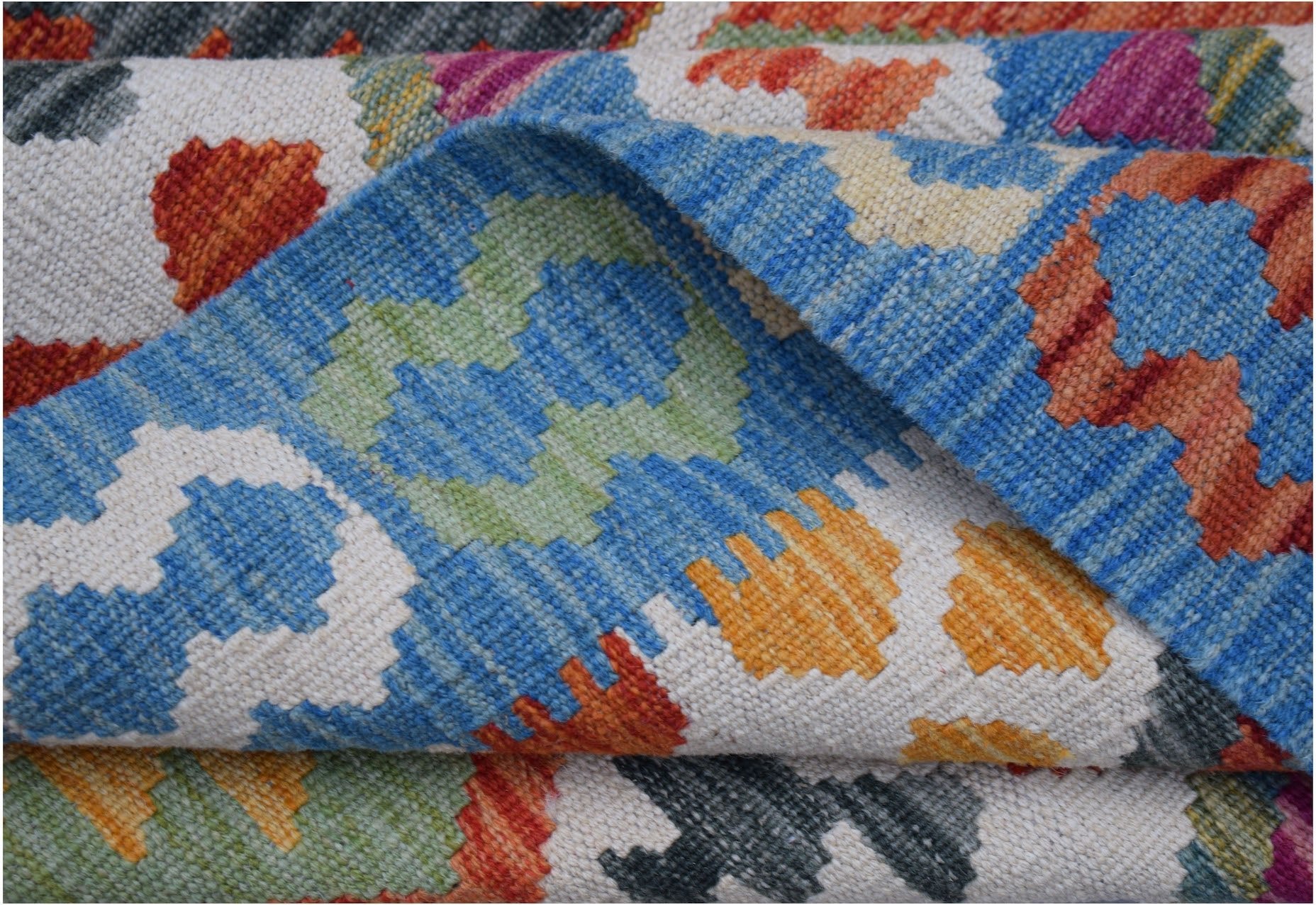 A handwoven Afghan Maimana kilim rug featuring a colorful geometric pattern on a white background.