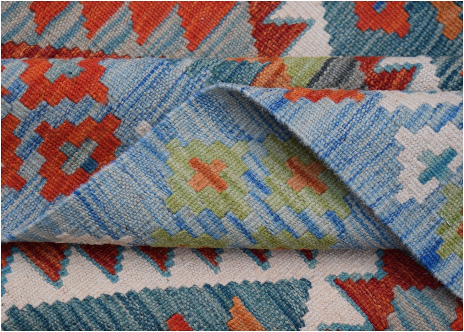 A handwoven Afghan Maimana kilim rug featuring a geometric pattern in blue, orange, and green.