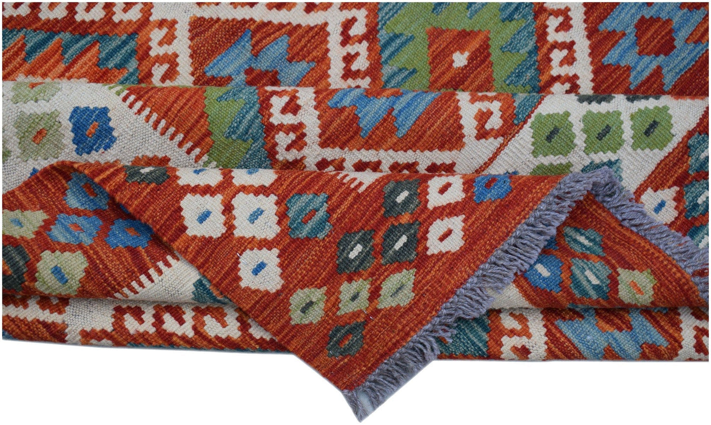 A handwoven Afghan Maimana kilim featuring geometric patterns in red, blue, green, and cream.