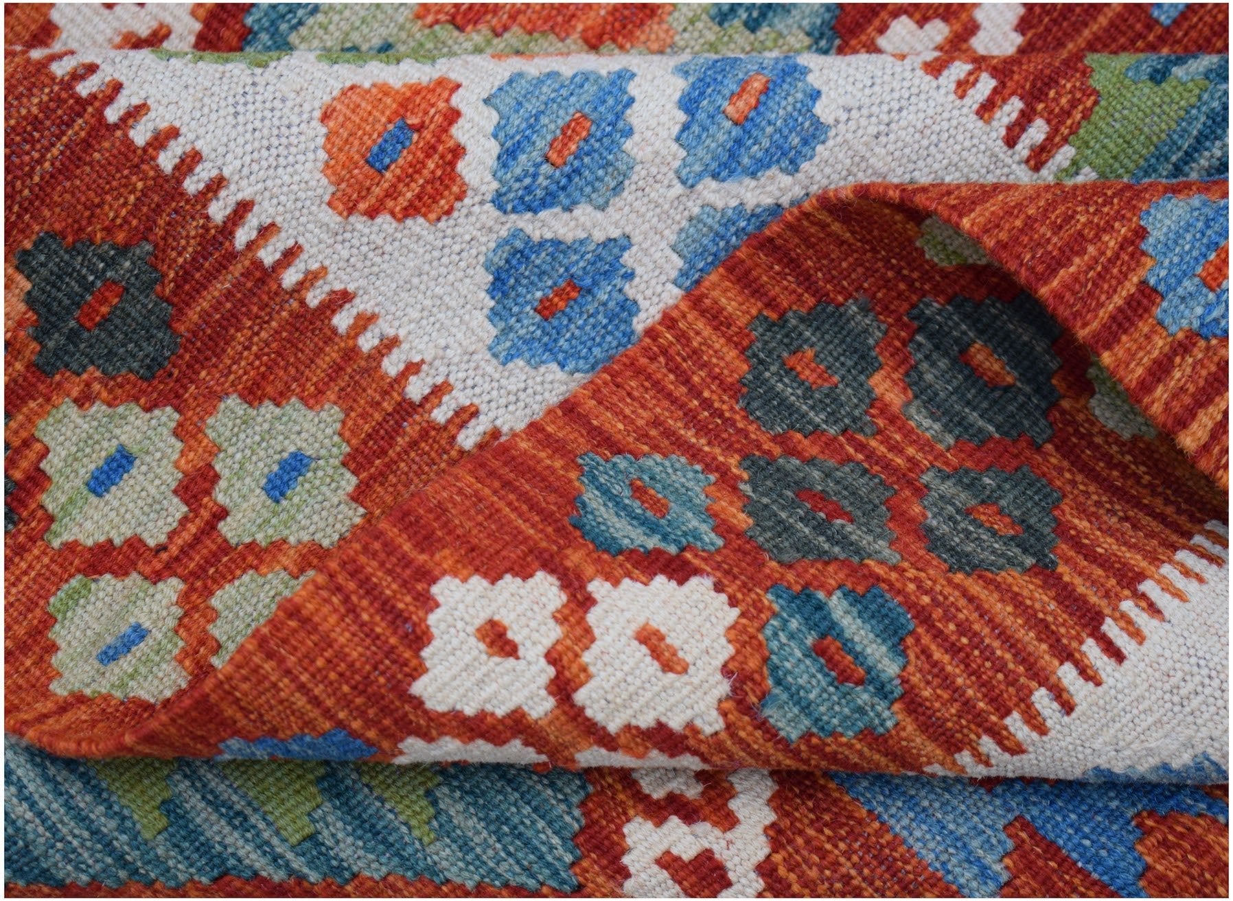 A handwoven Afghan Maimana kilim rug featuring a geometric pattern in orange, blue, and cream.
