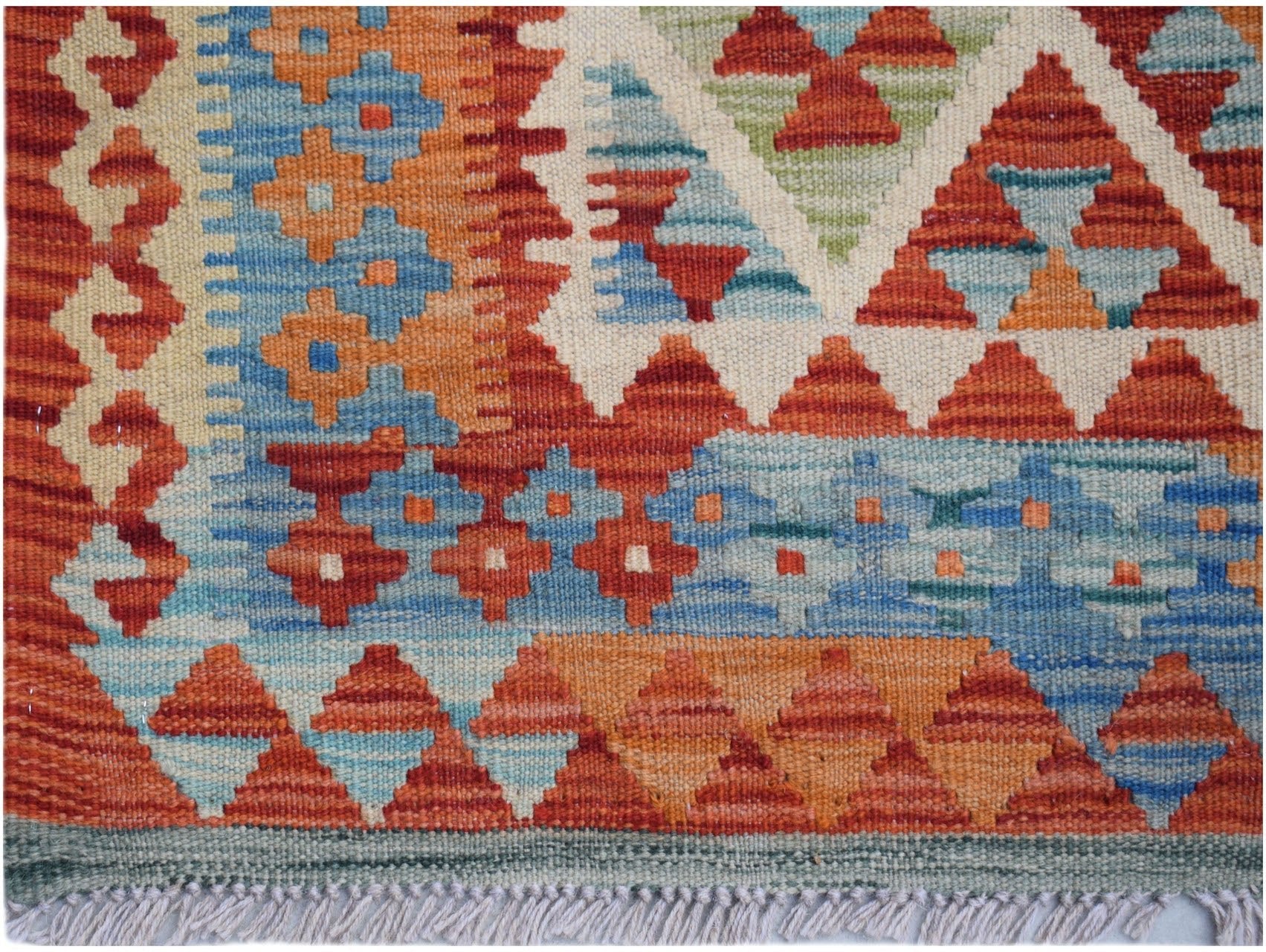 Handwoven Afghan Maimana kilim rug featuring a geometric pattern in vibrant red, blue, and orange.