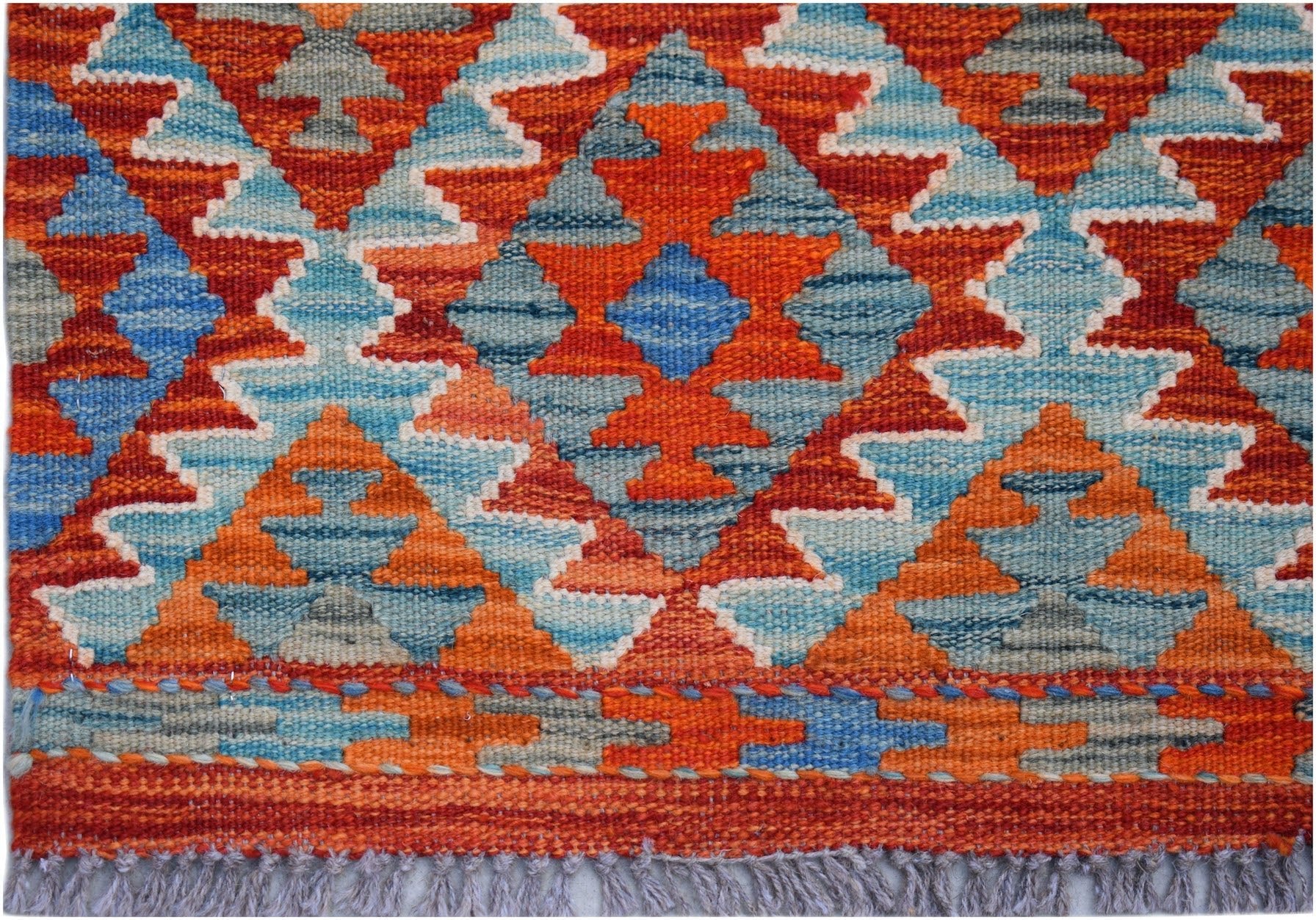 Handwoven Afghan Maimana kilim rug featuring a geometric diamond pattern in orange and blue tones.