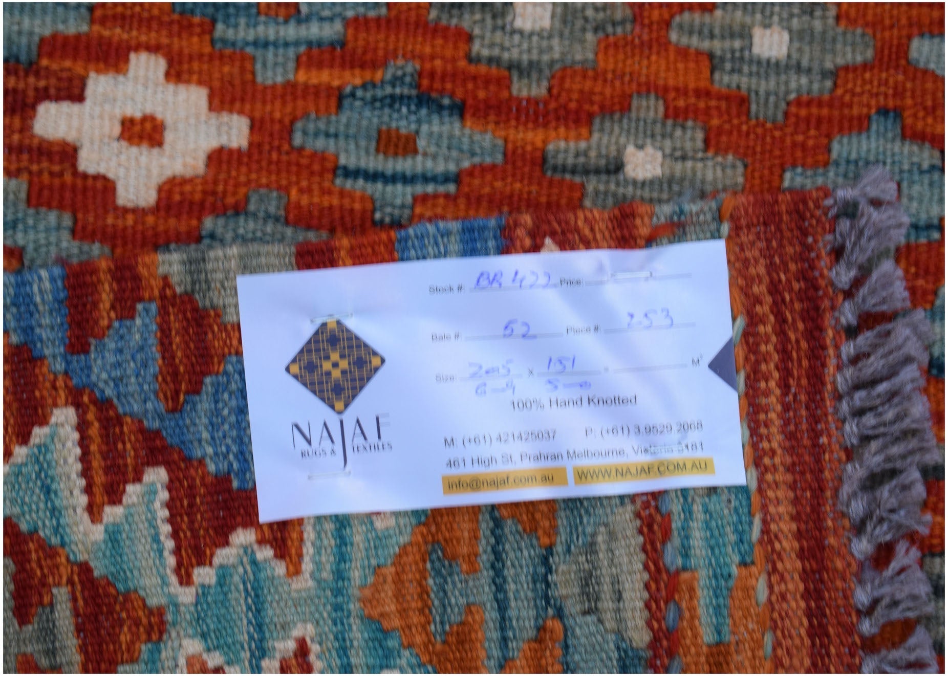 An Afghan Maimana Kilim rug featuring a geometric pattern in shades of orange, blue, and cream.