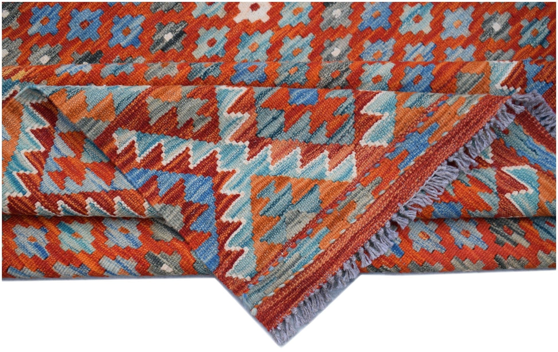 A handwoven Afghan Maimana kilim rug featuring a geometric pattern in orange, blue, and grey.