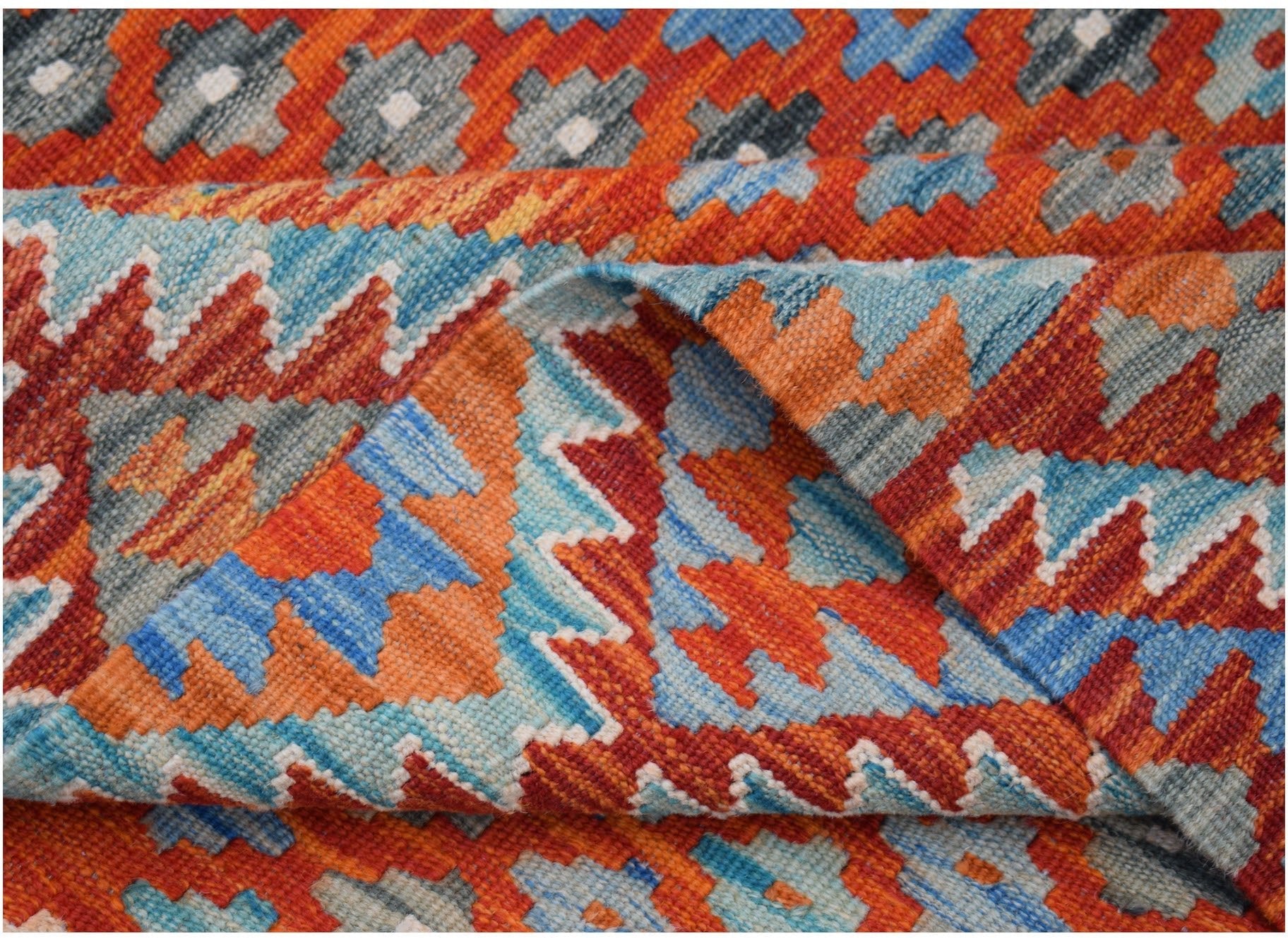 A handwoven Afghan Maimana kilim rug featuring a vibrant geometric pattern in orange and blue.