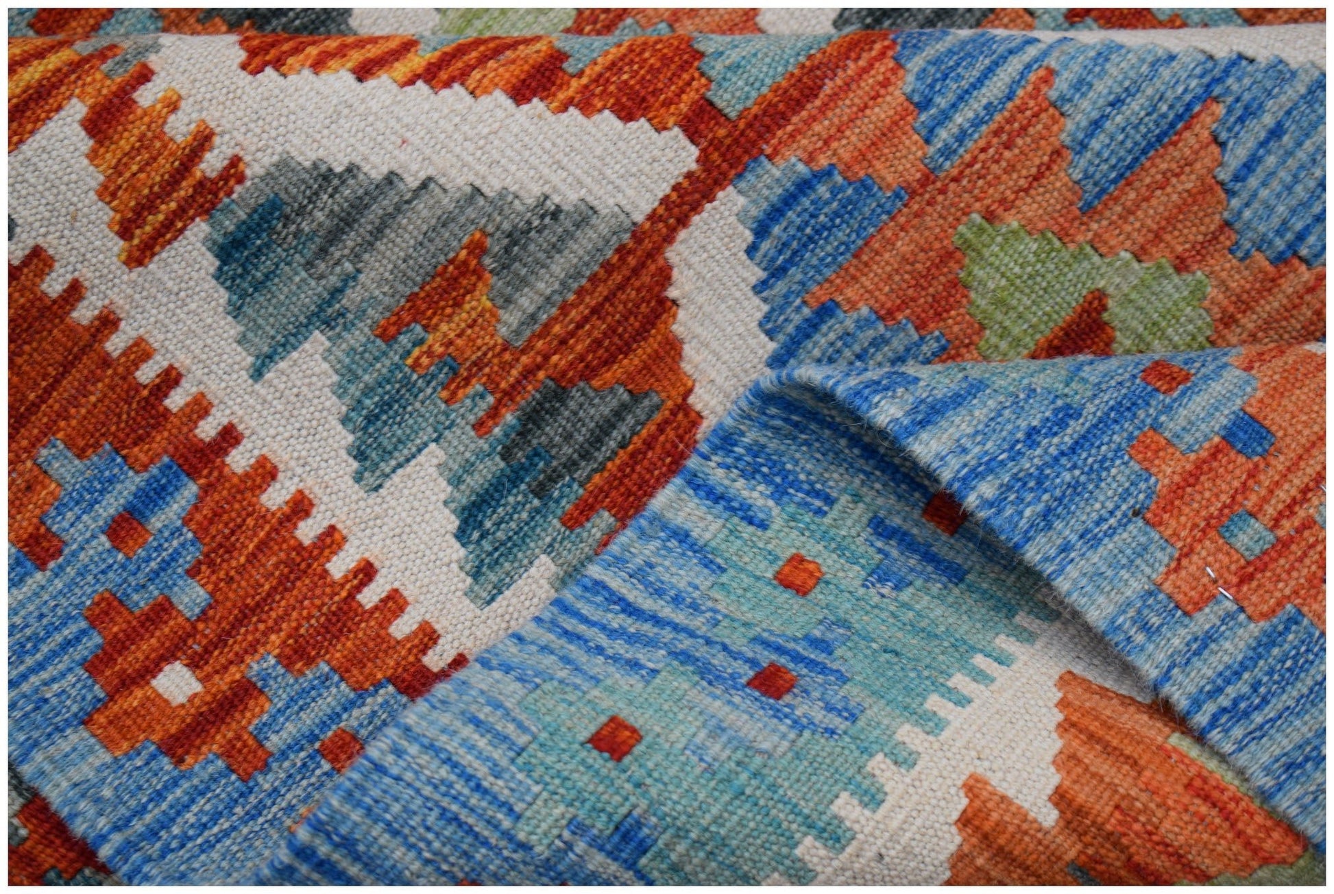 A handwoven Afghan Maimana kilim rug featuring a geometric pattern in orange, blue, and cream.