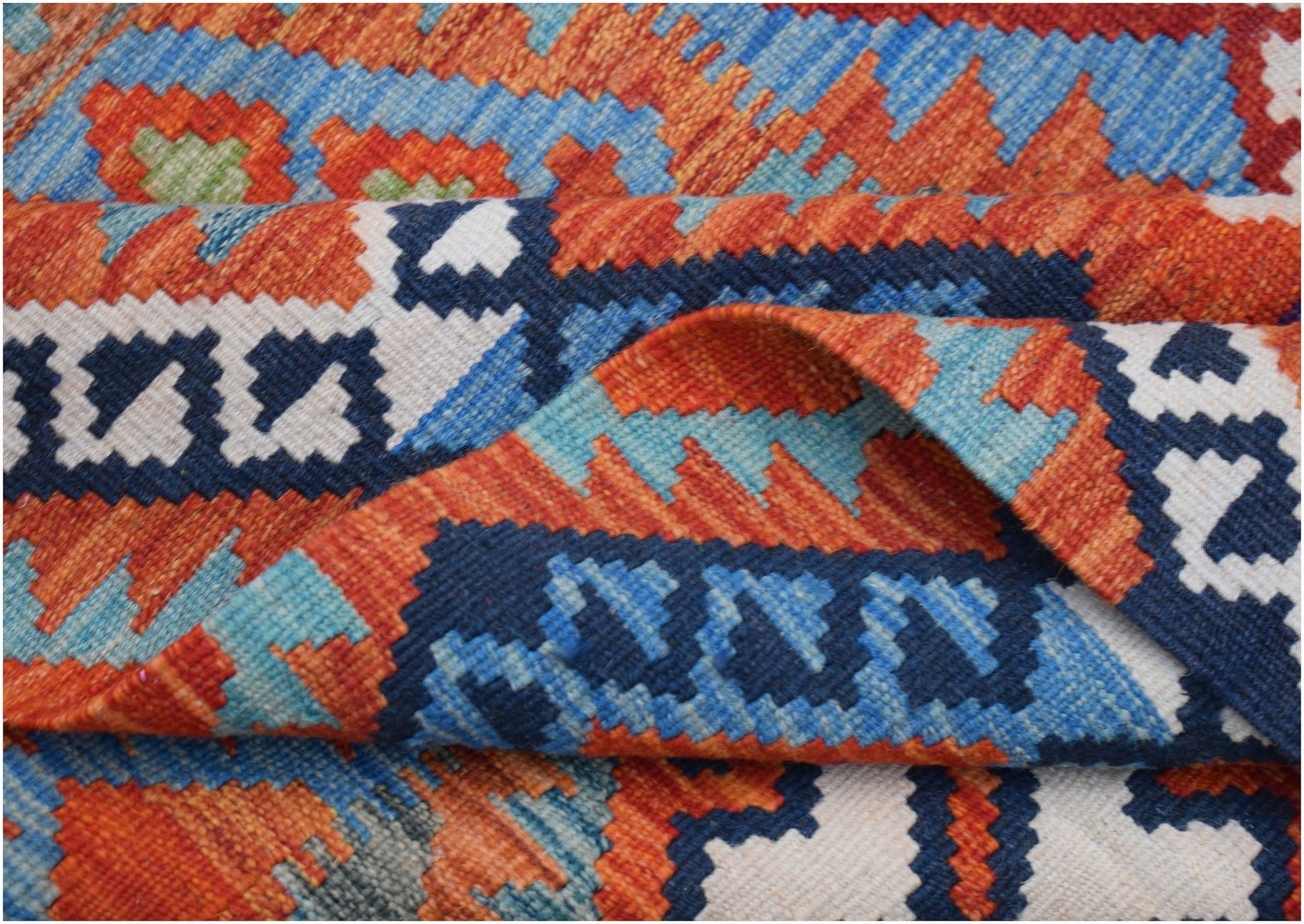 A handwoven Afghan Maimana kilim rug featuring a vibrant geometric pattern in wool.