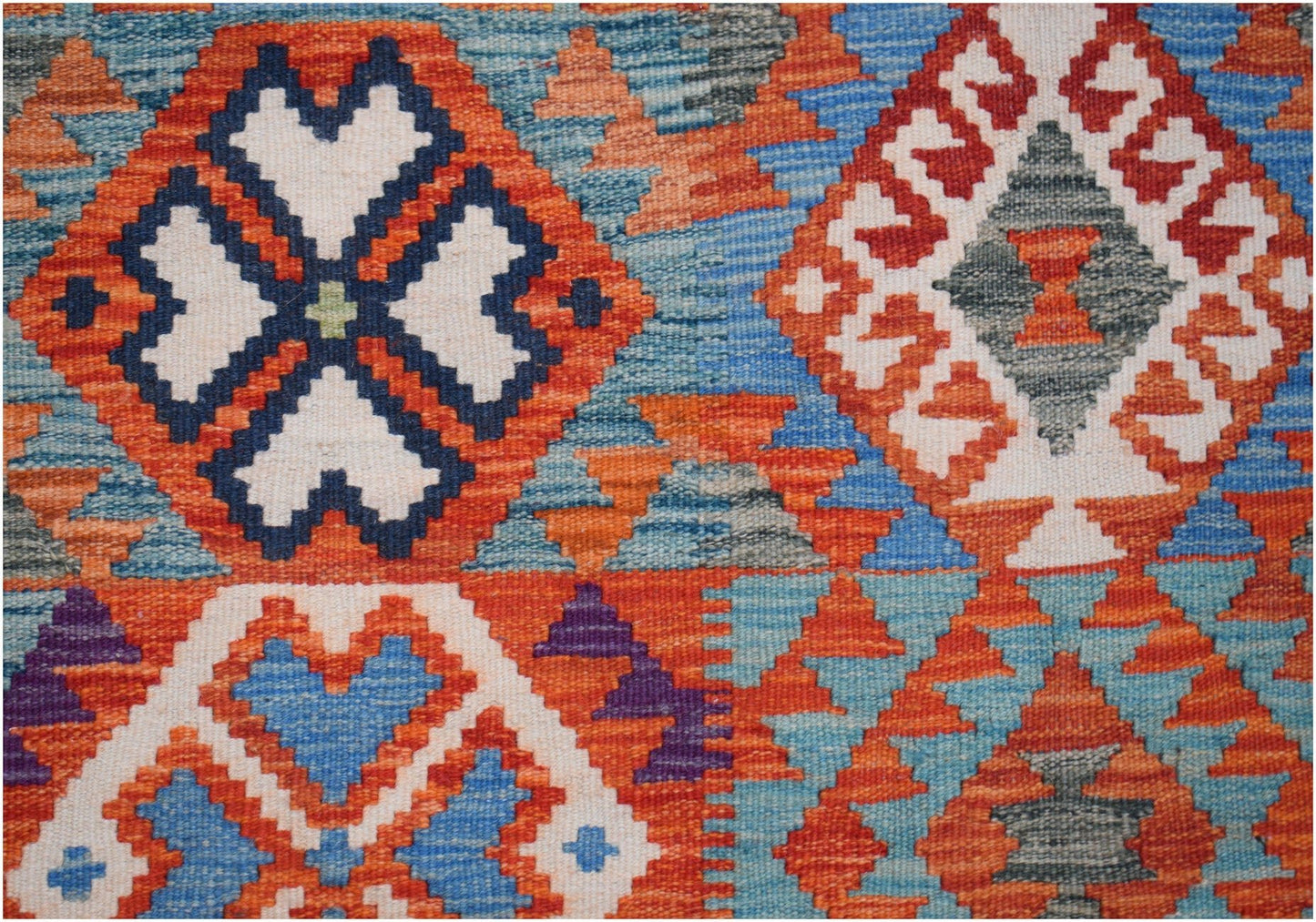 Handwoven Afghan Maimana kilim rug featuring a vibrant geometric pattern in wool.