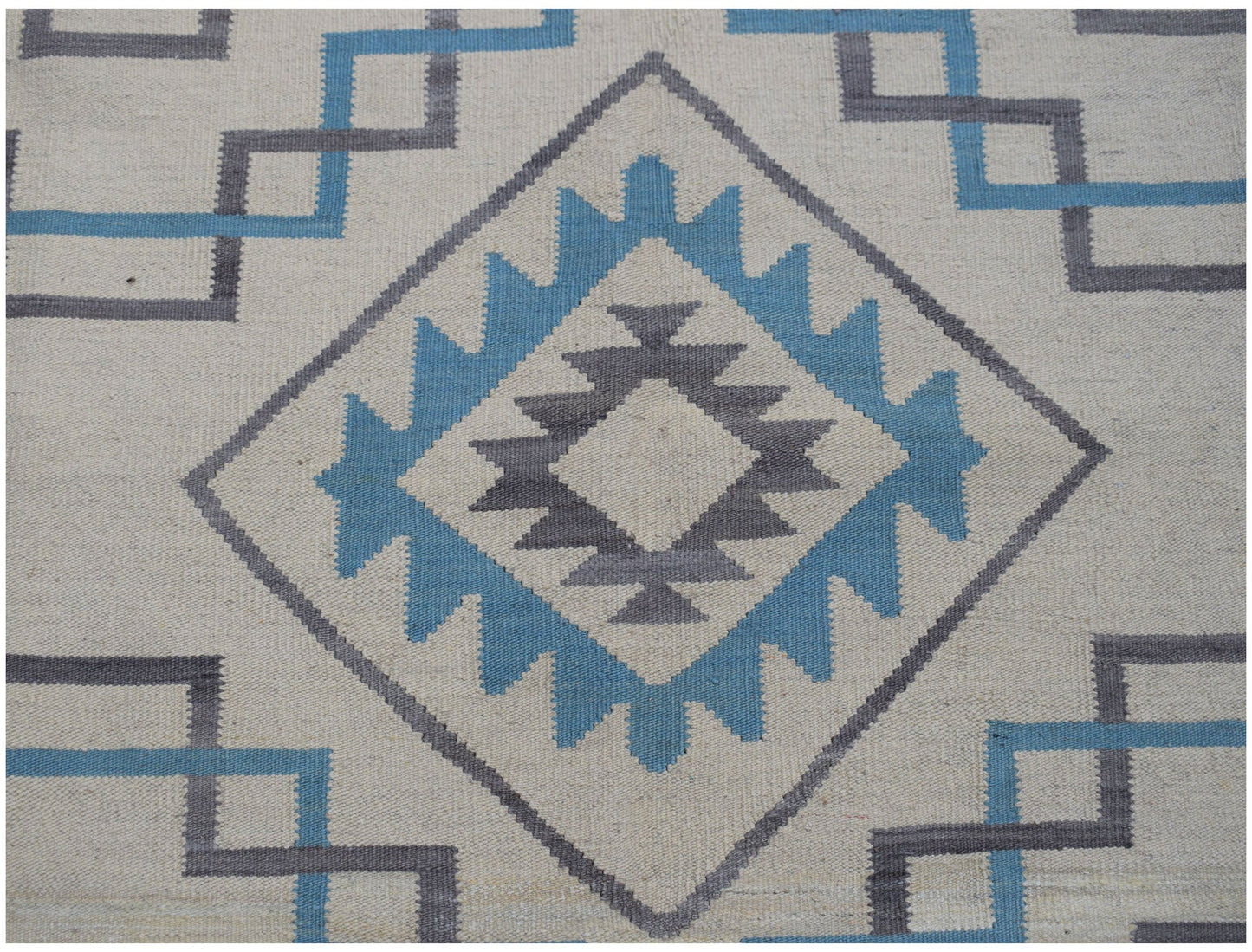 Handwoven Afghan Maimana kilim featuring a geometric diamond pattern in blue and grey on cream.