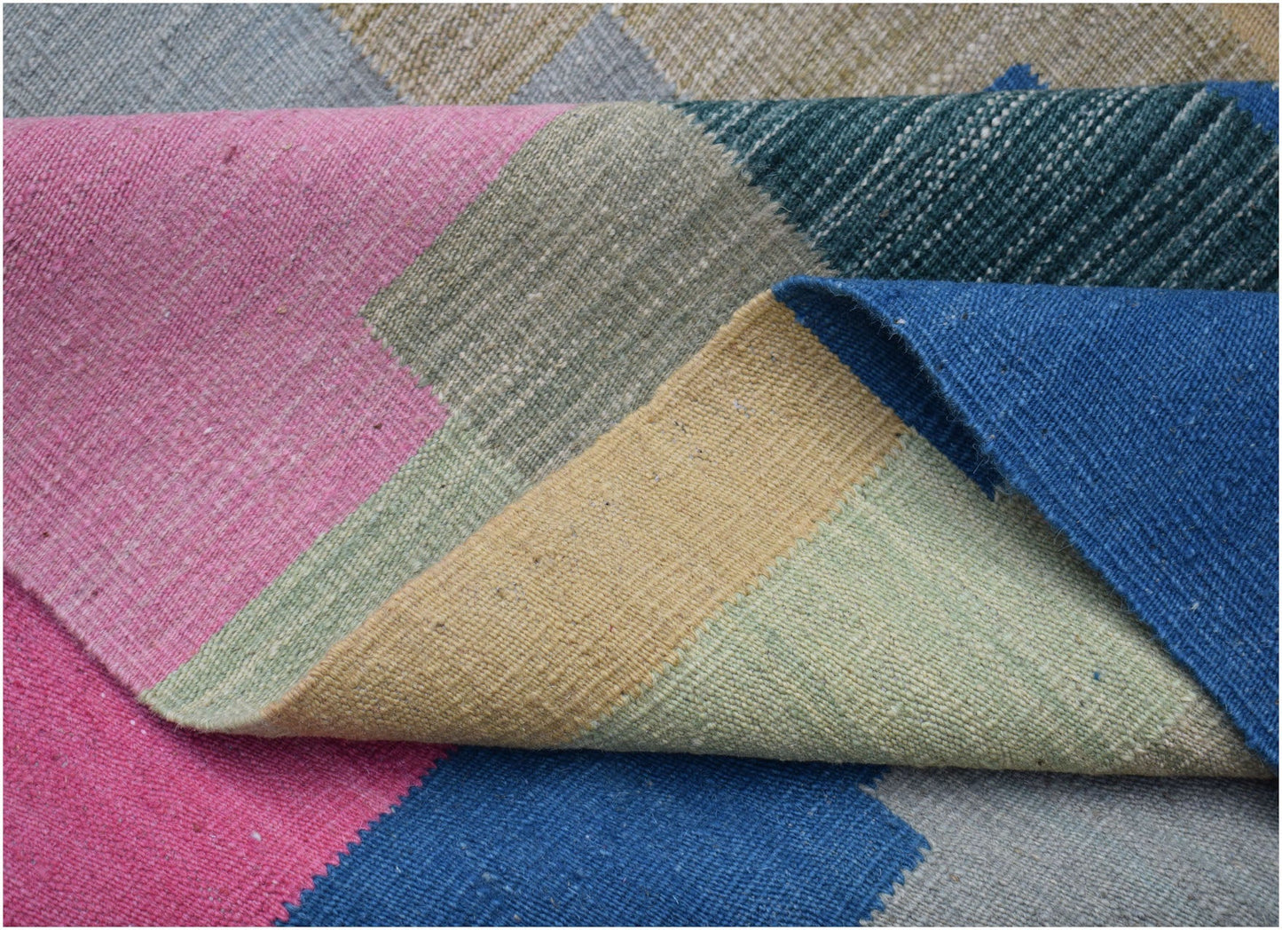 A handwoven Afghan Maimana kilim rug featuring a geometric pattern in vibrant multicolored blocks.